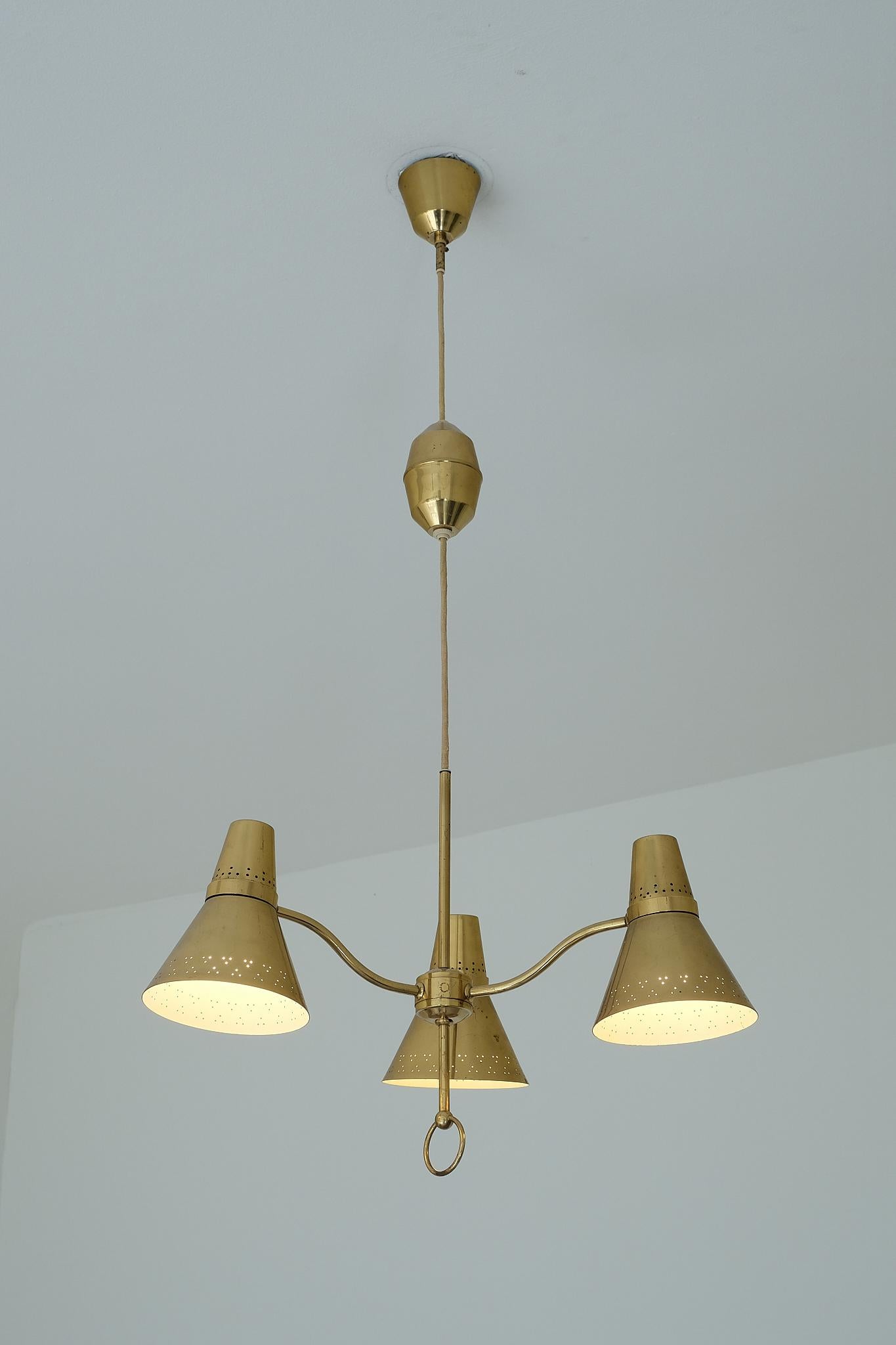 This striking three arm pendant light was manufactured by the company AB. E. Hansson in Mälmo, Sweden in the early 1950s. The entire design is made of brass and consists of a ceiling cup, cable holder and the fixture with three arms.
The brass