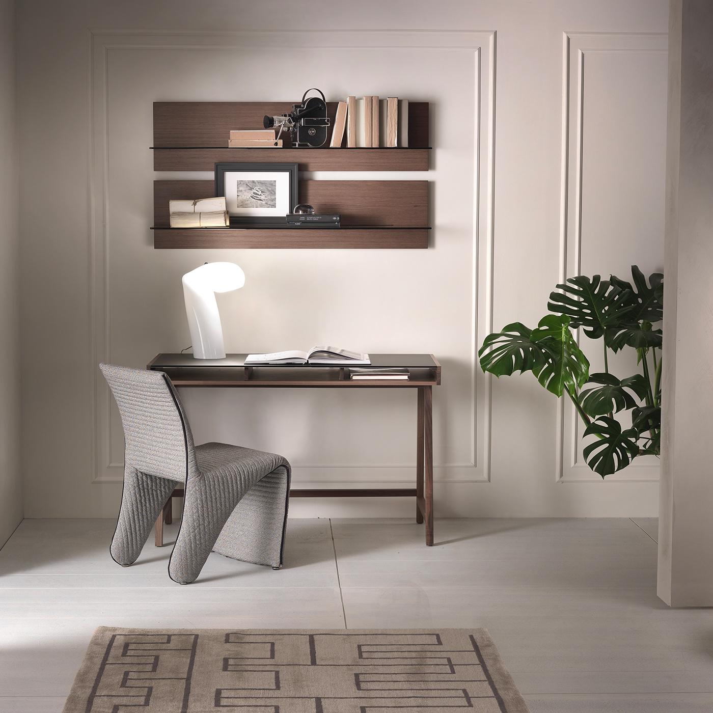 Prized materials and clean aesthetic effortlessly merge in this exquisite writing desk by Fabio Rebosio. The structure is crafted of Canaletto walnut wood and enriched with a matte bronze-lacquered tempered glass top, while the shelf features a