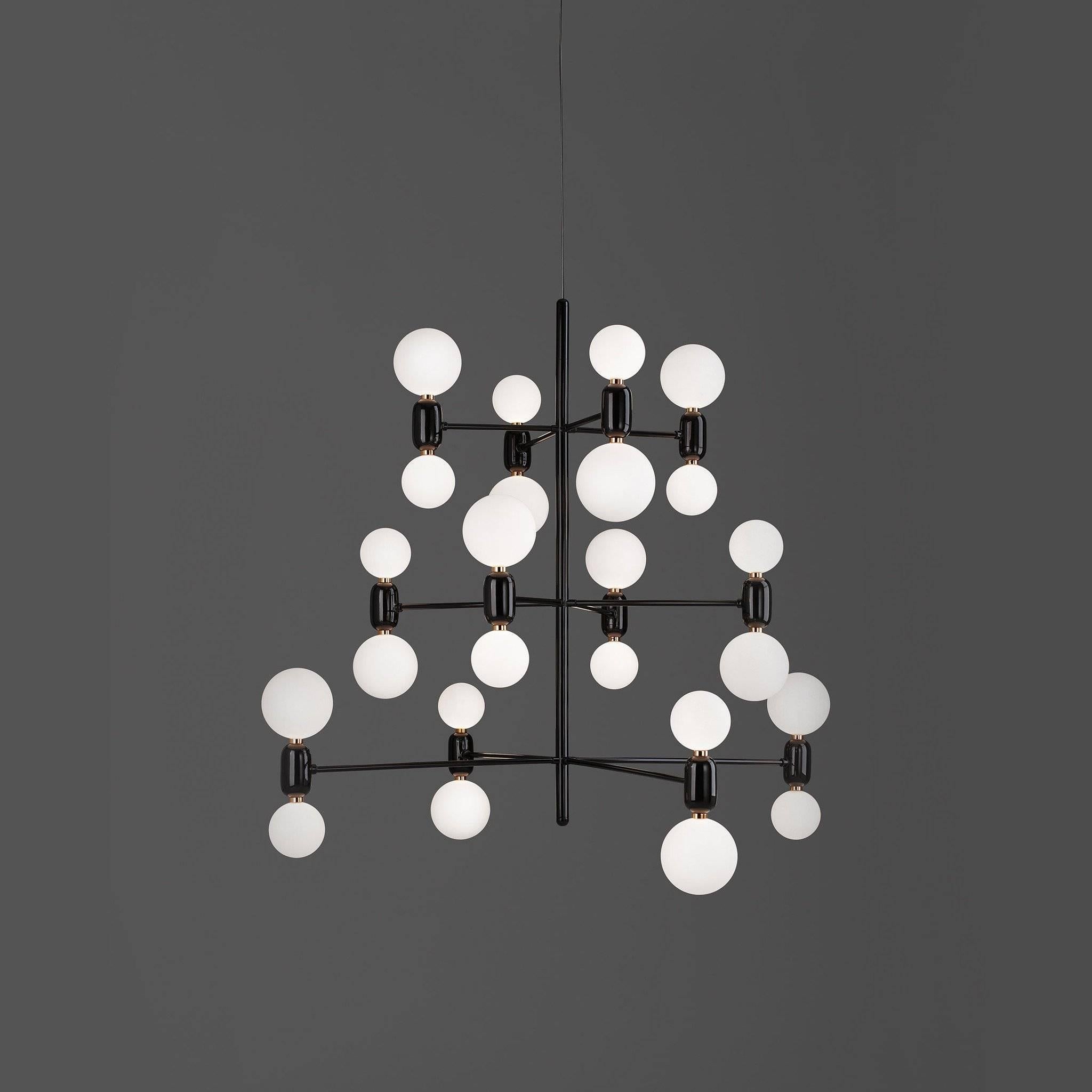The chandelier showcases a lacquered steel structure matching the color of the 24 blown glass diffusers ceramic bodies completing the fixture. The result is a set of strongly decorative objects that produce a warm ambient light and can be used in a
