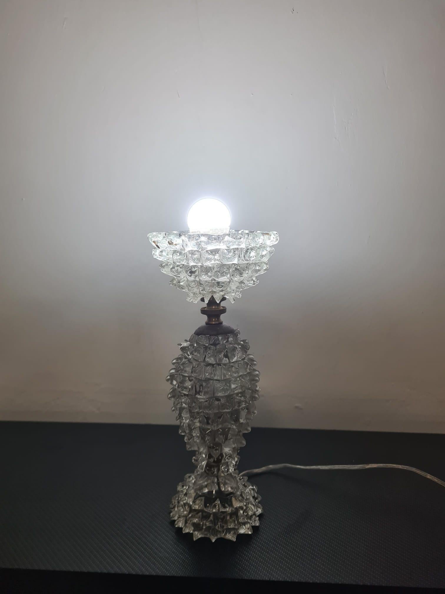 Abat-jour Ercole Barovier

Lampe de table en verre rocailleux d'Ercole Barovier.

La rostration du verre est une technique spéciale qui consiste à tirer le verre à chaud à l'aide d'une pince pour former des points.

Cette technique a été inventée et