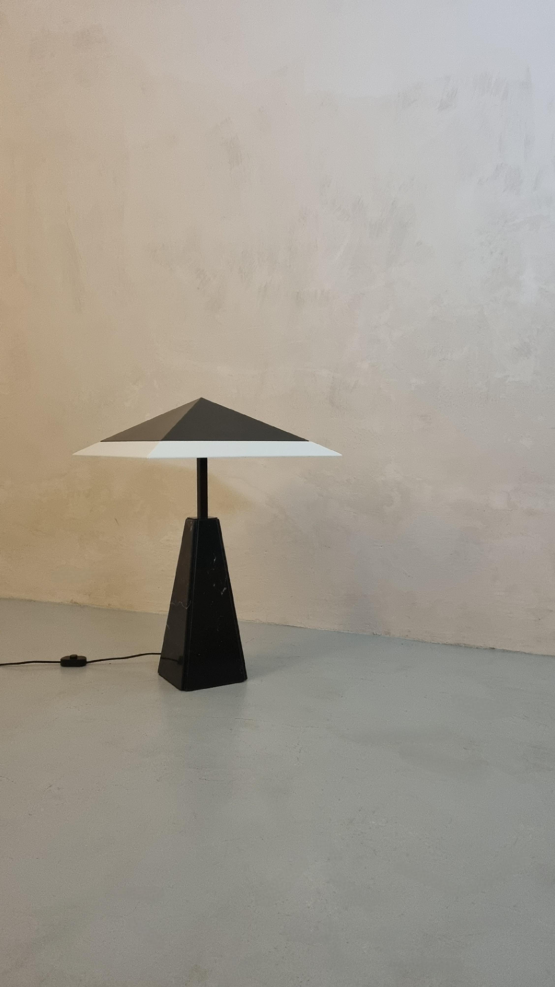 Lampada da tavolo modello Abat Jour disegnata da Cini Boeri nel 1970 per Arteluce, prima produzione.
Base in marmo nero marquina, struttura in acciaio verniciato, paralume in perspex e lamiera verniciata, la lampada monta 4 lampadine.
Una rara prima