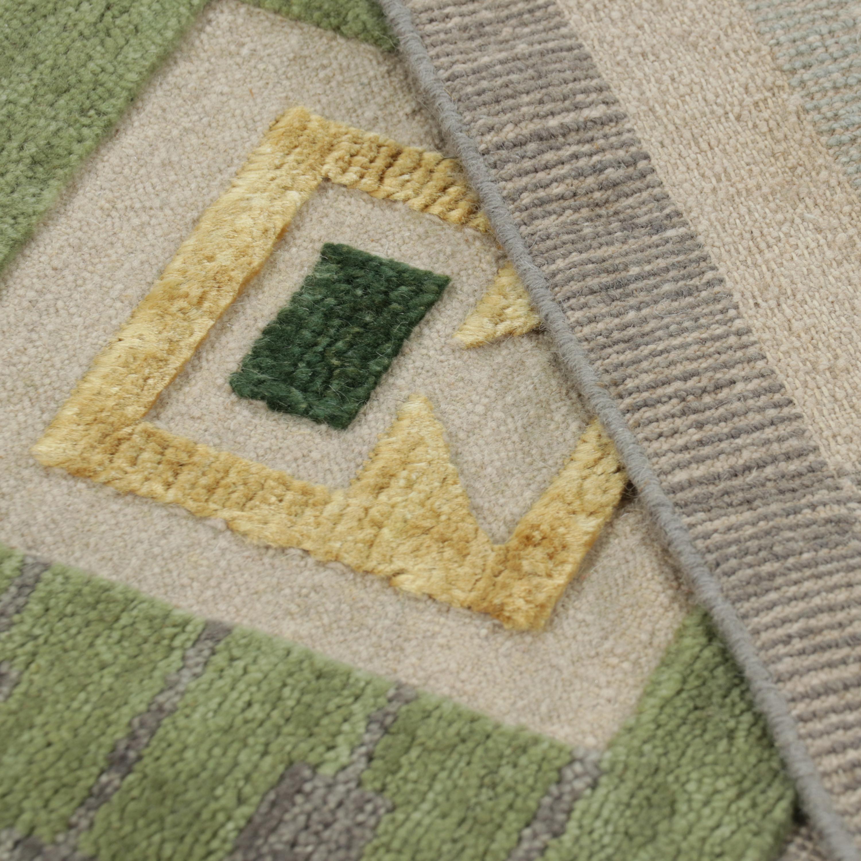 This Blue & Green Swedish Inspired Flatweave Wool Rug features a geometric pattern of squares and rectangles in muted shades of green, blue, red, brown, gray, and yellow. Hand woven in India with wool and silk, this high-quality rug is a versatile