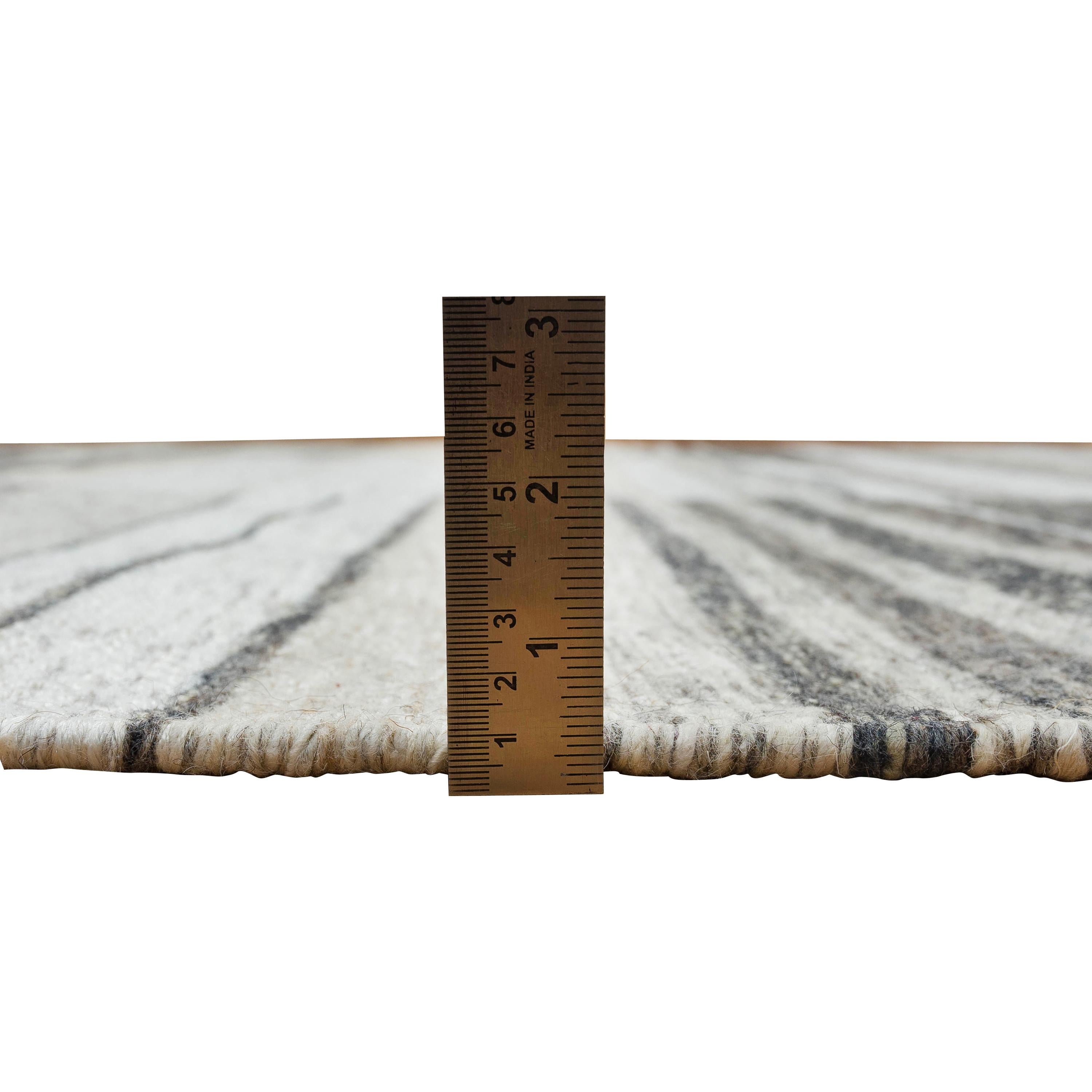 Ce tapis en laine Dhurrie d'inspiration suédoise, mesurant 8' x 10', présente un motif géométrique moderne dans différentes nuances de gris. Noué à la main en Inde, ce tapis de haute qualité présente un design équilibré avec un mélange de tons