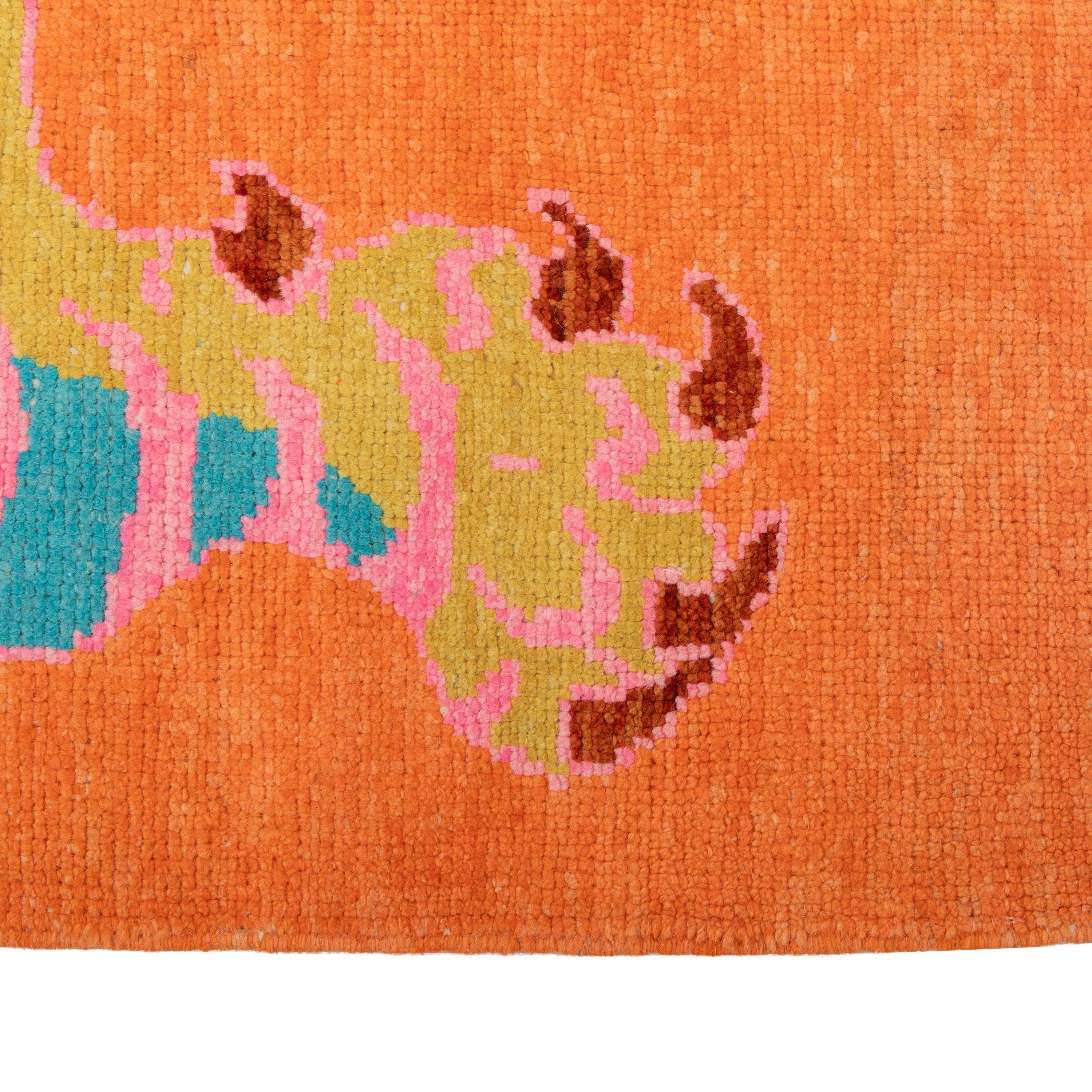 This Orange Contemporary Tiger Wool Rug features a whimsical pattern of a stylized tiger in shades of blue and pink on a vibrant orange background. Hand-knotted in Turkey, this high-quality wool rug measures 5'7