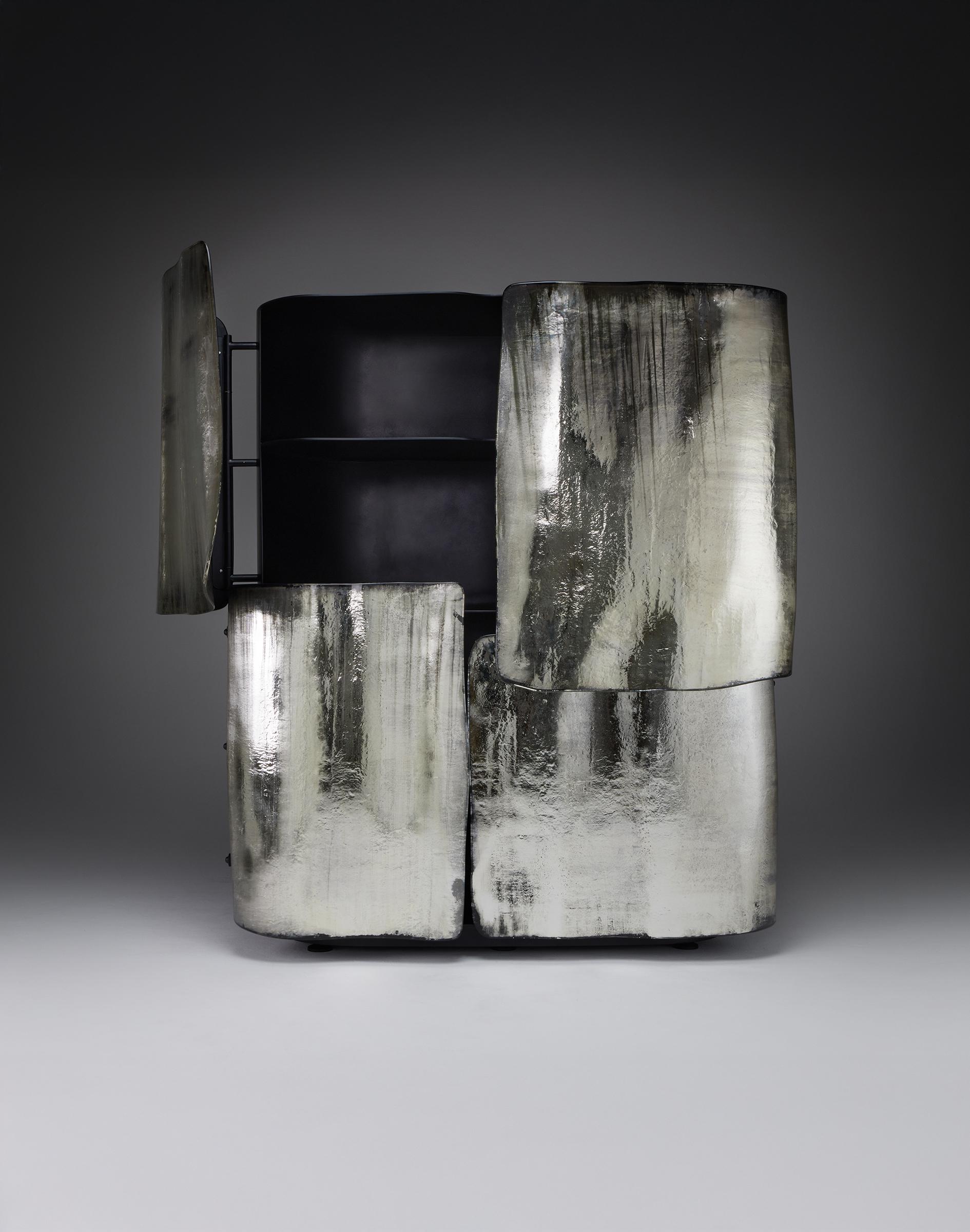 Abditio è un mobile dalla forza tranquilla e dalla presenza deliberata. Quattro sostanziali porte di vetro, le cui superfici sono sottilmente specchiate, nascondono e rivelano in egual misura, passando dalla trasparenza all'opacità con il gioco