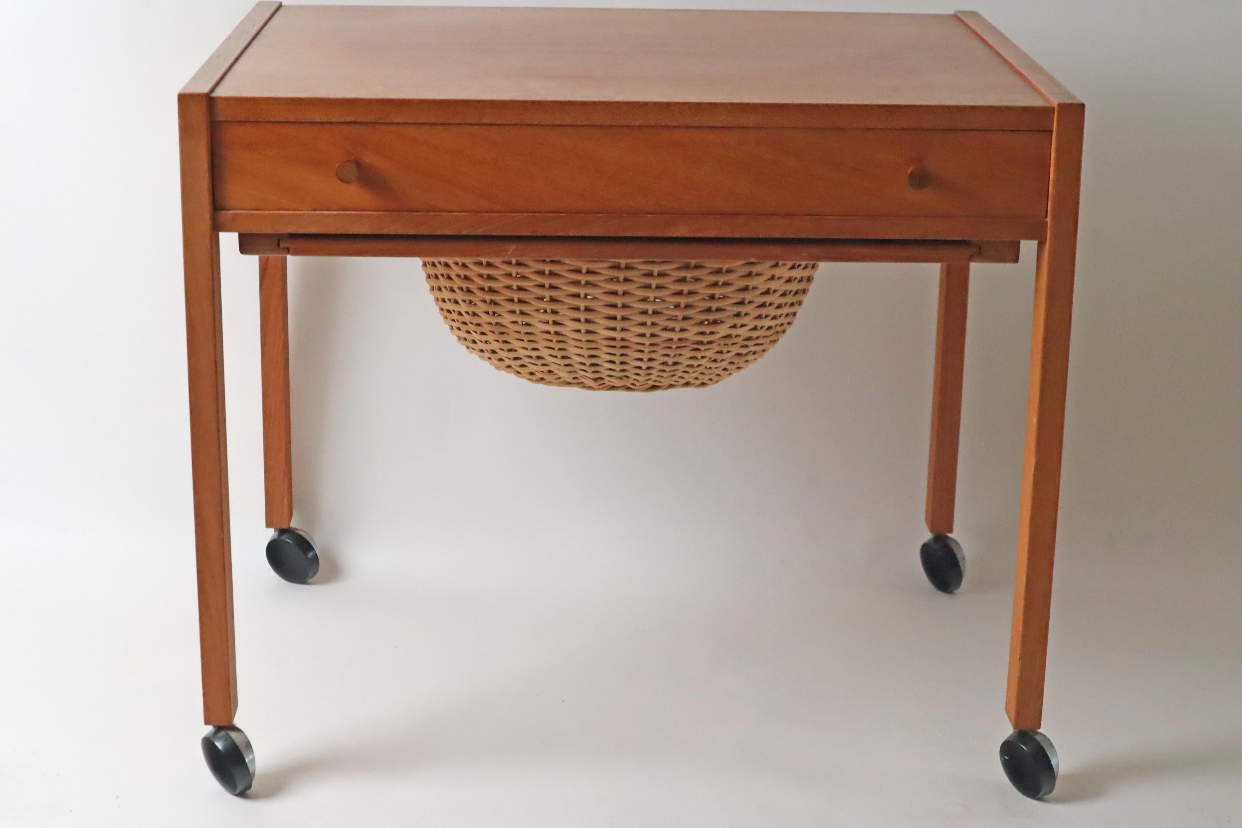 Je vous présente une table d'appoint avec un panier en rotin datant des années 1950. Cette table est originaire d'Europe et plus précisément du Danemark.  Cette table dispose d'un tiroir et d'un panier en rotin extractible pour le rangement.  Cette