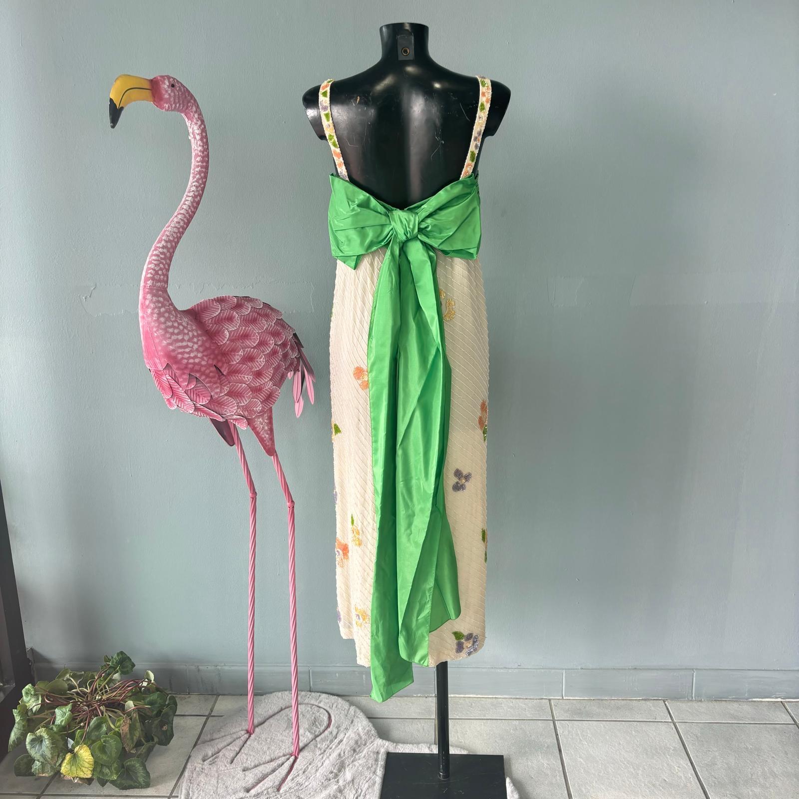 Abito sartoriale in pailettes verde e panna 
L'abito interamente in pailettes con fiori presenta una fascia verde sul seno che va a formare un grande fiocco sulla schiena

Misure:
Spalle 42cm
Petto 49cm
Lunghezza 127cm
