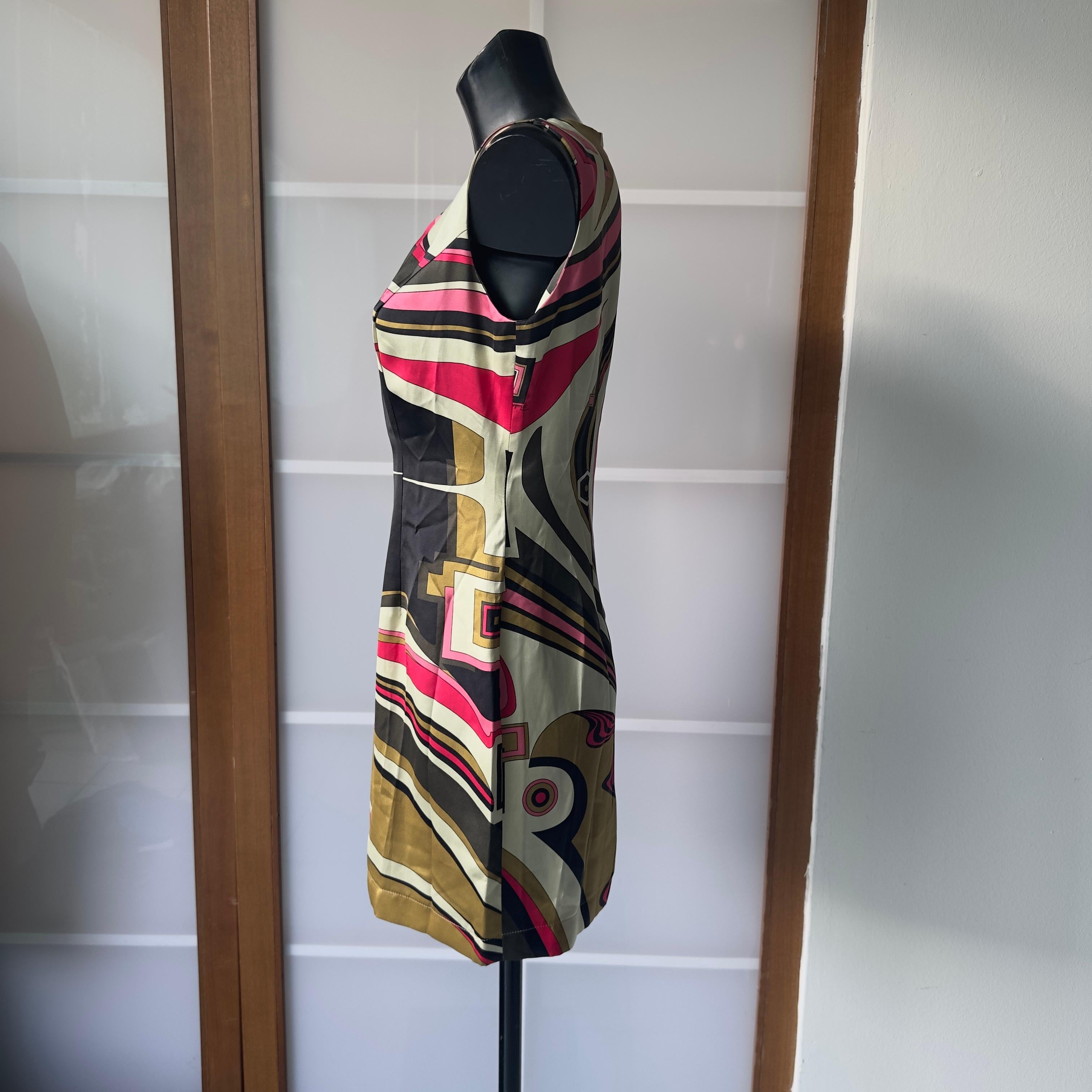 Iconico abito smanicato firmato Emilio Pucci, risalente agli anni 2000, realizzato in pura seta con stampa psichedelica tipica della maison. Le linee fluide e il taglio sartoriale valorizzano la silhouette con un’eleganza grafica inconfondibile. I