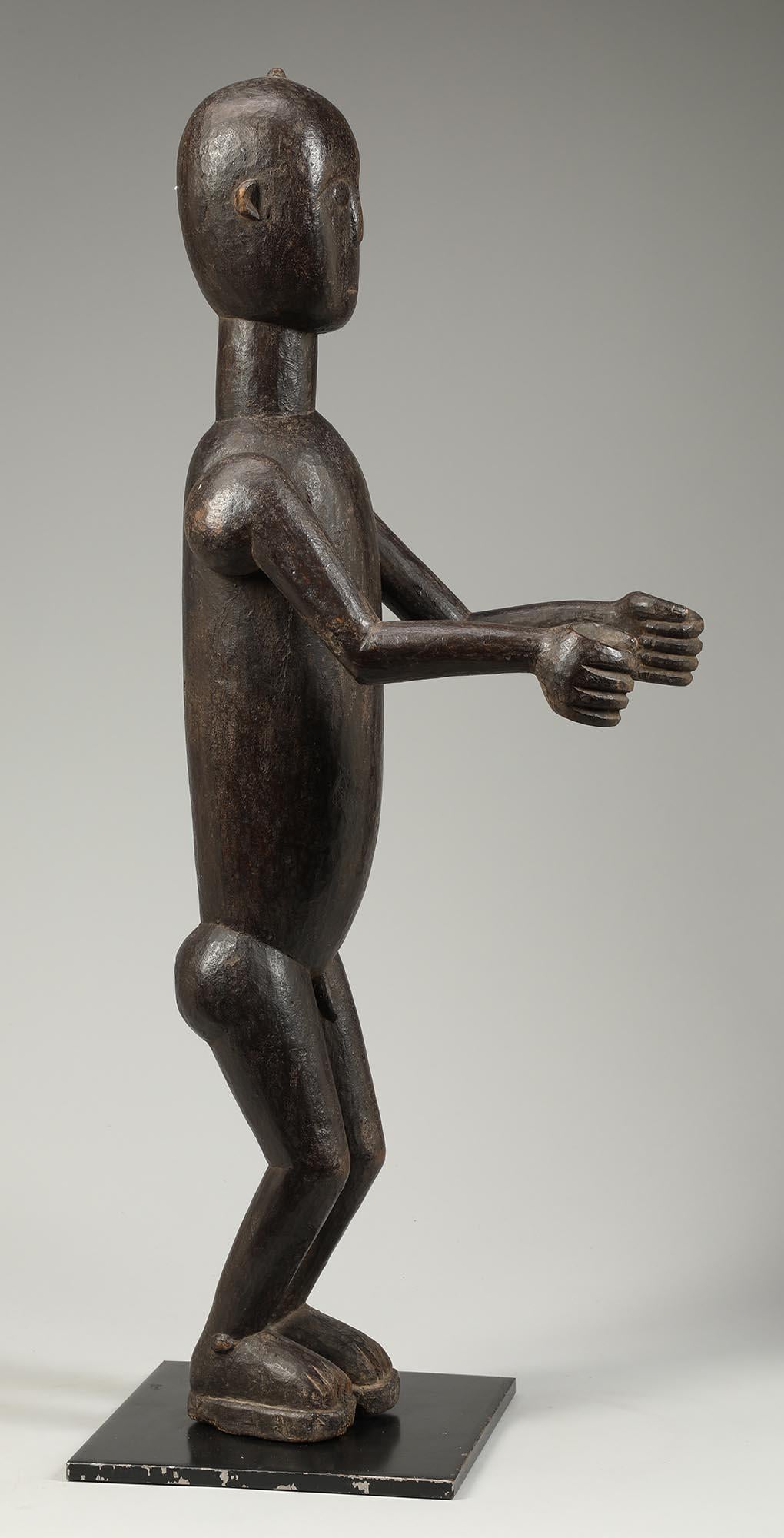 Abron Drum Attendant standing figure with both arms out front. From Ghana, early 20th century. Rich, dark patina to the surface.
A wonderful streamlined (really Art Deco in feeling) or cubist style dancing male figure from a drum ensemble. The