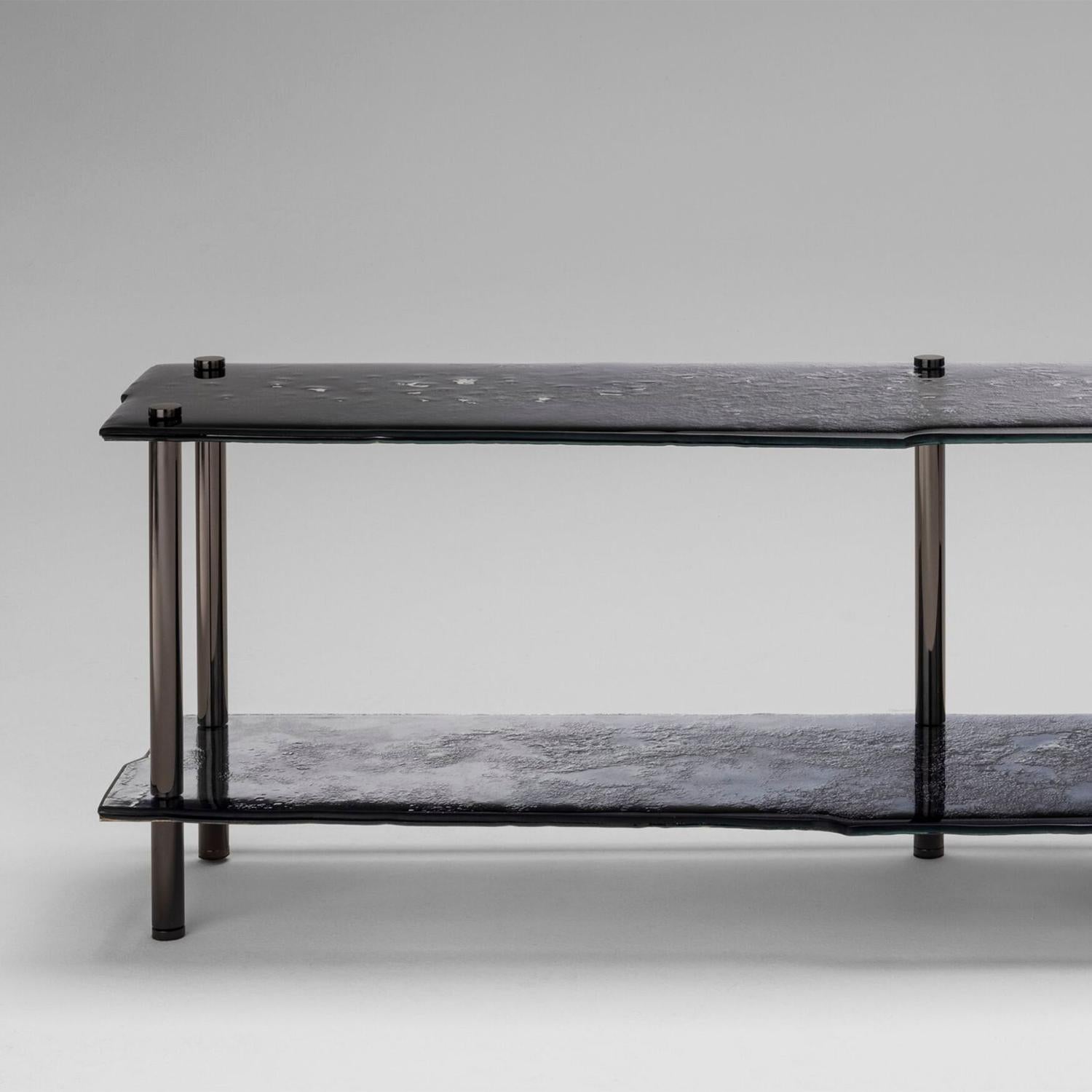 Table console Abruz avec plateaux hauts et bas en 2 couches
verre cuit avec des bords irréguliers en gradient de profondeur
bleu foncé à transparent avec dos partiellement argenté.
avec une structure de pieds en fer en finition nickel foncé poli.
