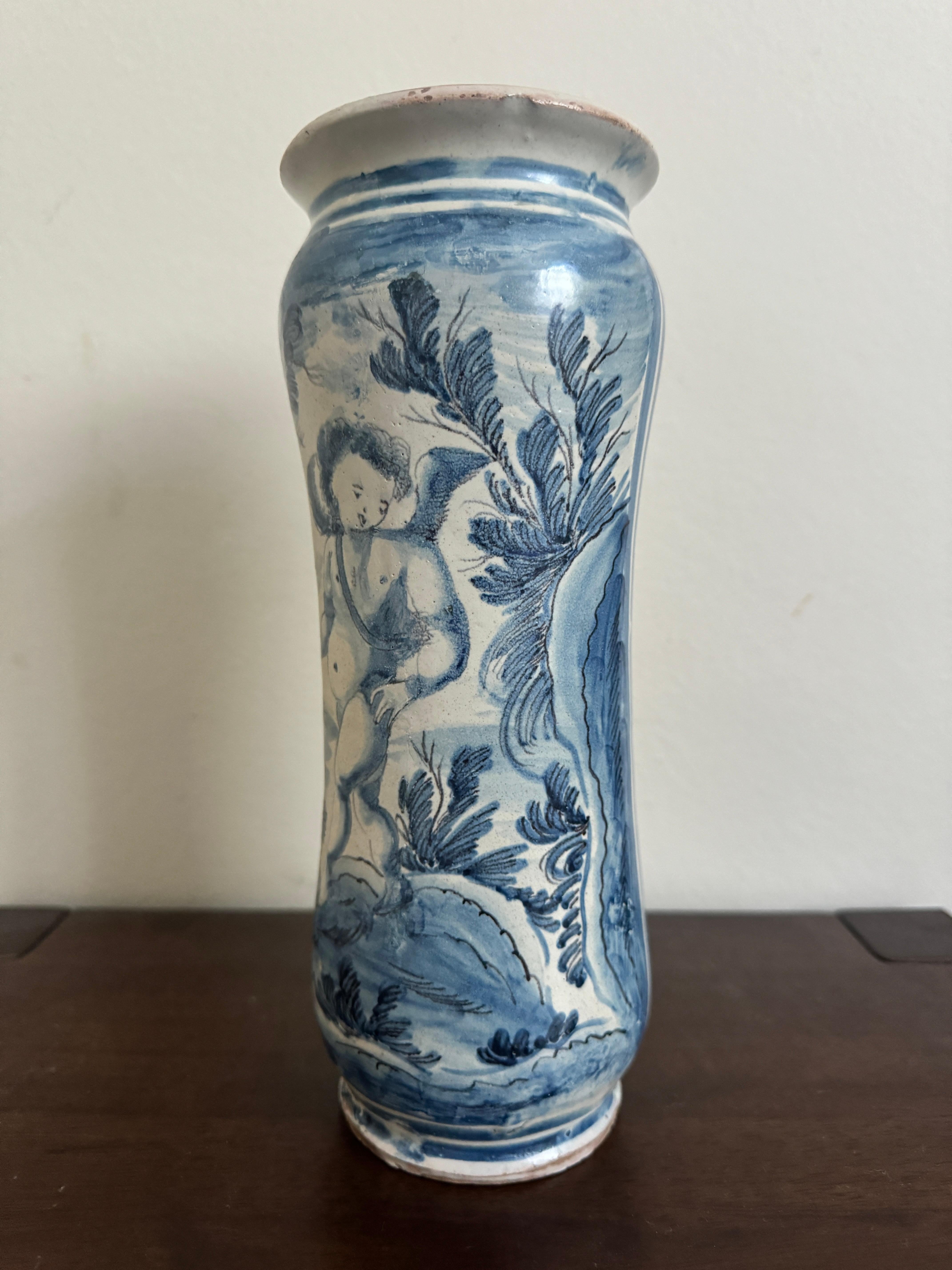 Una maiolica abruzzese 'albarelli' in buone condizioni.

Smalto di stagno bianco, forma cilindrica a vita decorata in blu, con una figura classica di putto circondata da alberi e fiori. 

Fine del XVII o inizio del XVIII secolo, altezza 10 pollici. 