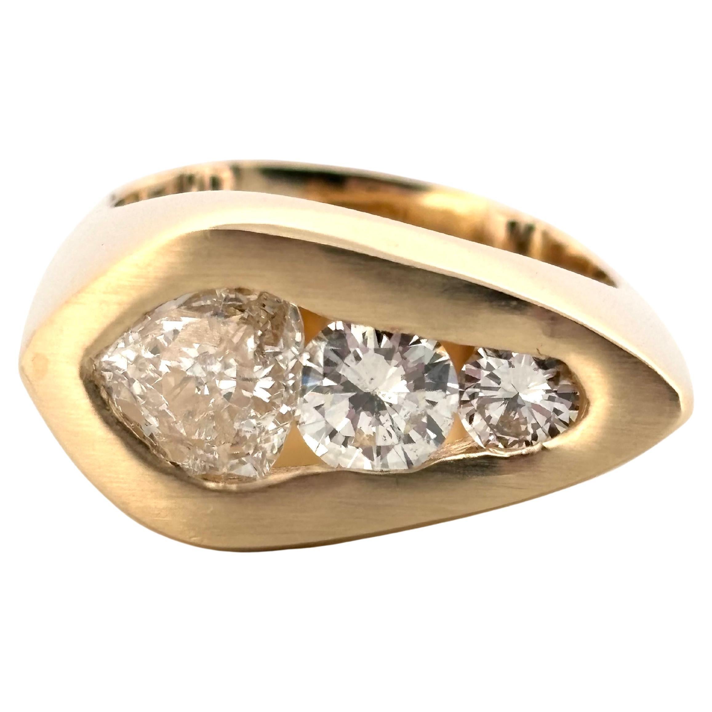 Este diseño atrevido y escultural muestra una disposición abstracta de diamantes naturales engastados en una ancha banda de oro amarillo de 14 quilates muy pulida. En su corazón yace un llamativo diamante talla trillón de 0,67 qt, de color J-K y