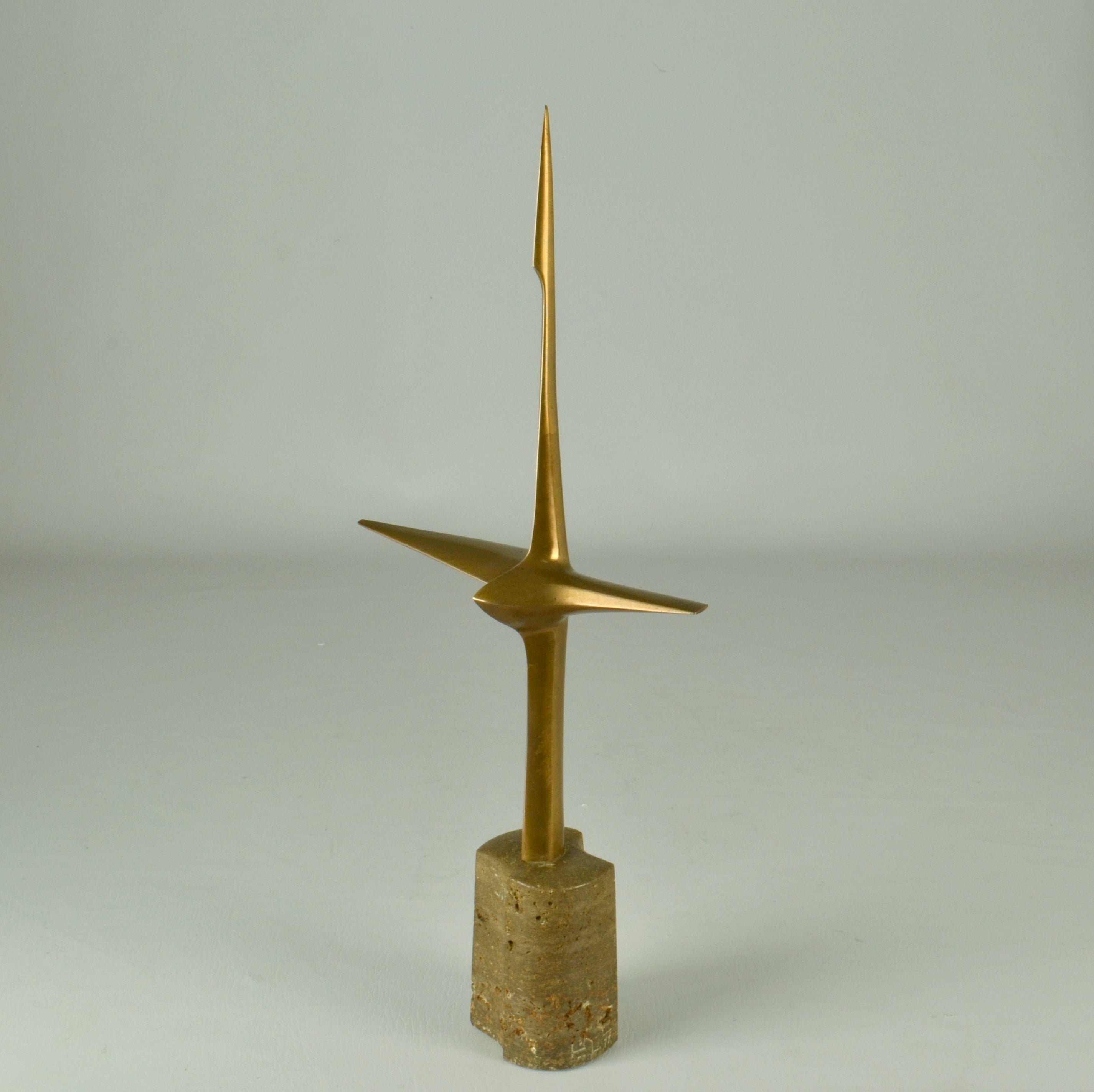 Abstract aerodynamic cast bronze sculpture is in take-off perched on a tower shaped granite rock, as a bird that must generate enough airflow across the span of its wings to create the lift for an upward jump. The aerodynamic form gives the