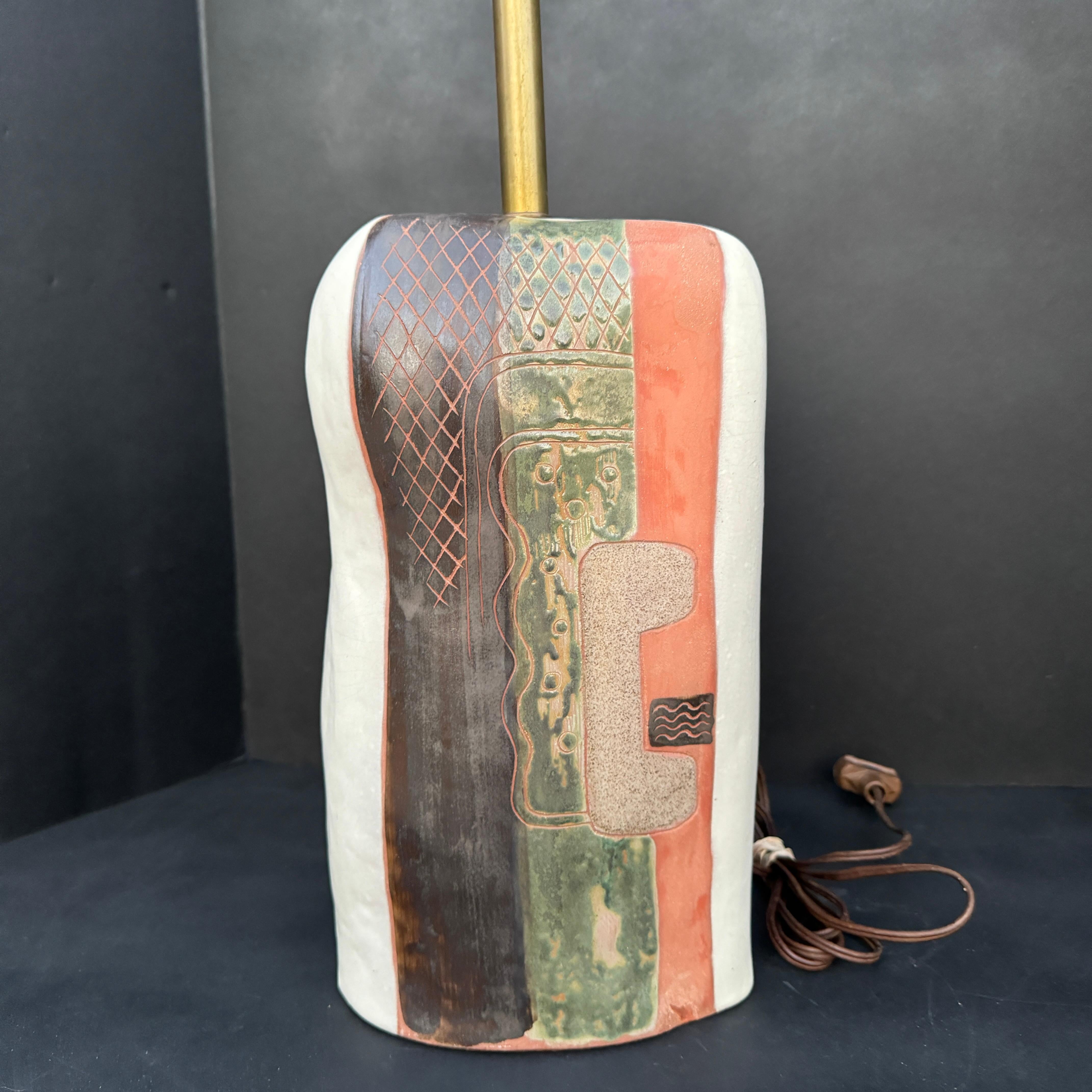 Fantastic, art pottery, table lamp by German-born, American artist, Marianna von Allesch features a 27.5 inch height to the top of the harp/finial, organically shaped, terra cotta, ceramic body with painted abstract forms and incised patterns,