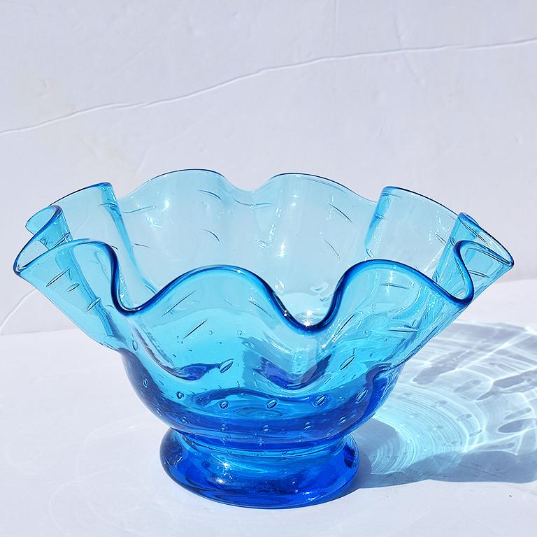 Beautiful bright blue faceted scalloped or draped Murano glass bowl or vessel. This draped bowl is round or handkerchief in form and features a cinched bottom and open wide top with dramatic wavy or scalloped edges. The color is transparent blue
