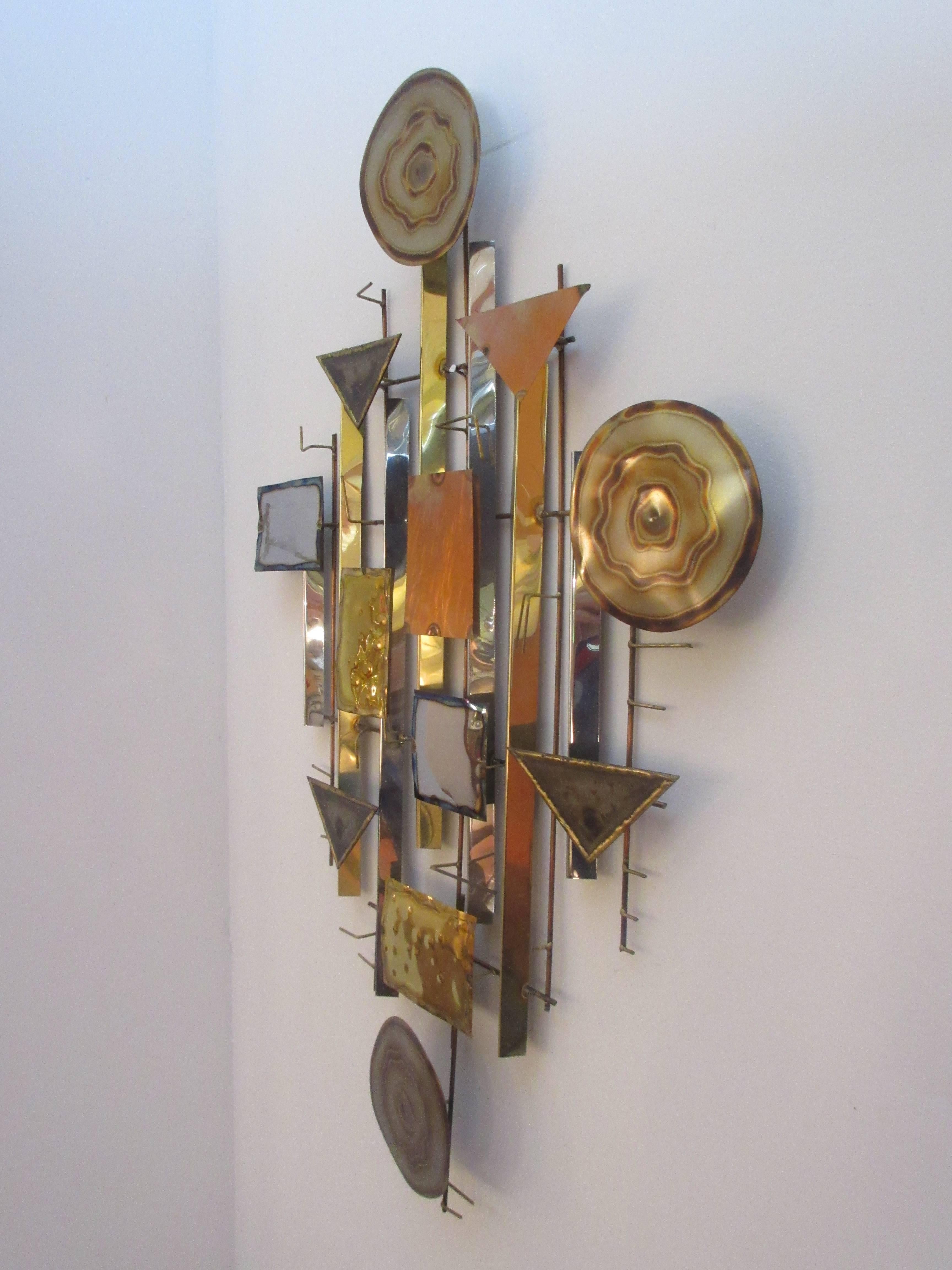 Abstract metal wall sculpture in the style if C. Jere with an indecipherable signature shown on last picture. Sculpture consists of triangles, rectangles, and circles of burnished brass, copper and sheet metal held together with a round brass wire.