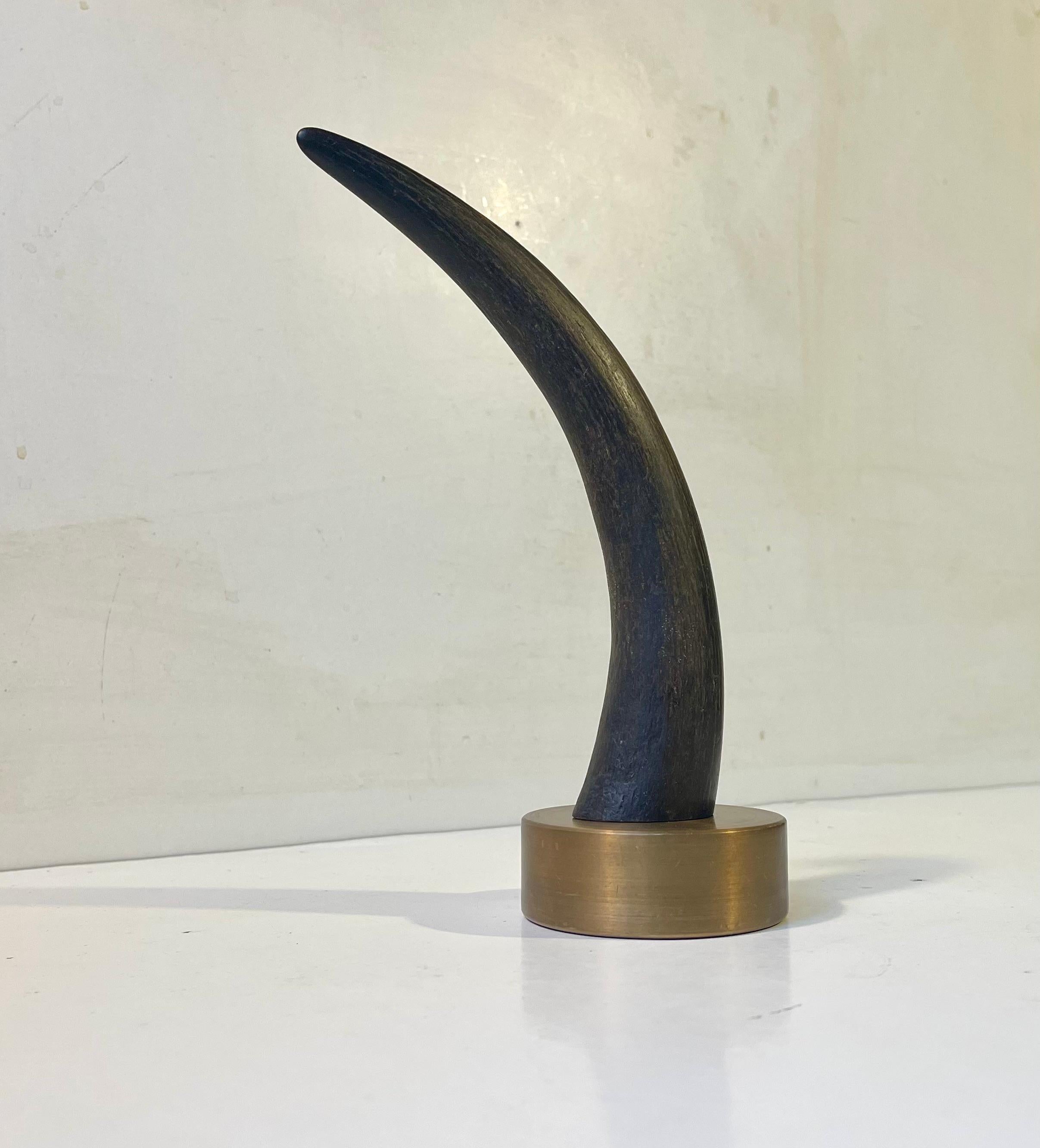 Inusual pisapapeles o escultura de escritorio formada por un pesado disco de bronce del que sobresale una pieza decorativa de cuerno viejo negro/marrón oscuro de un Yak (desmontable). Fabricado anónimamente en Escandinavia durante los años 60 ó 70.