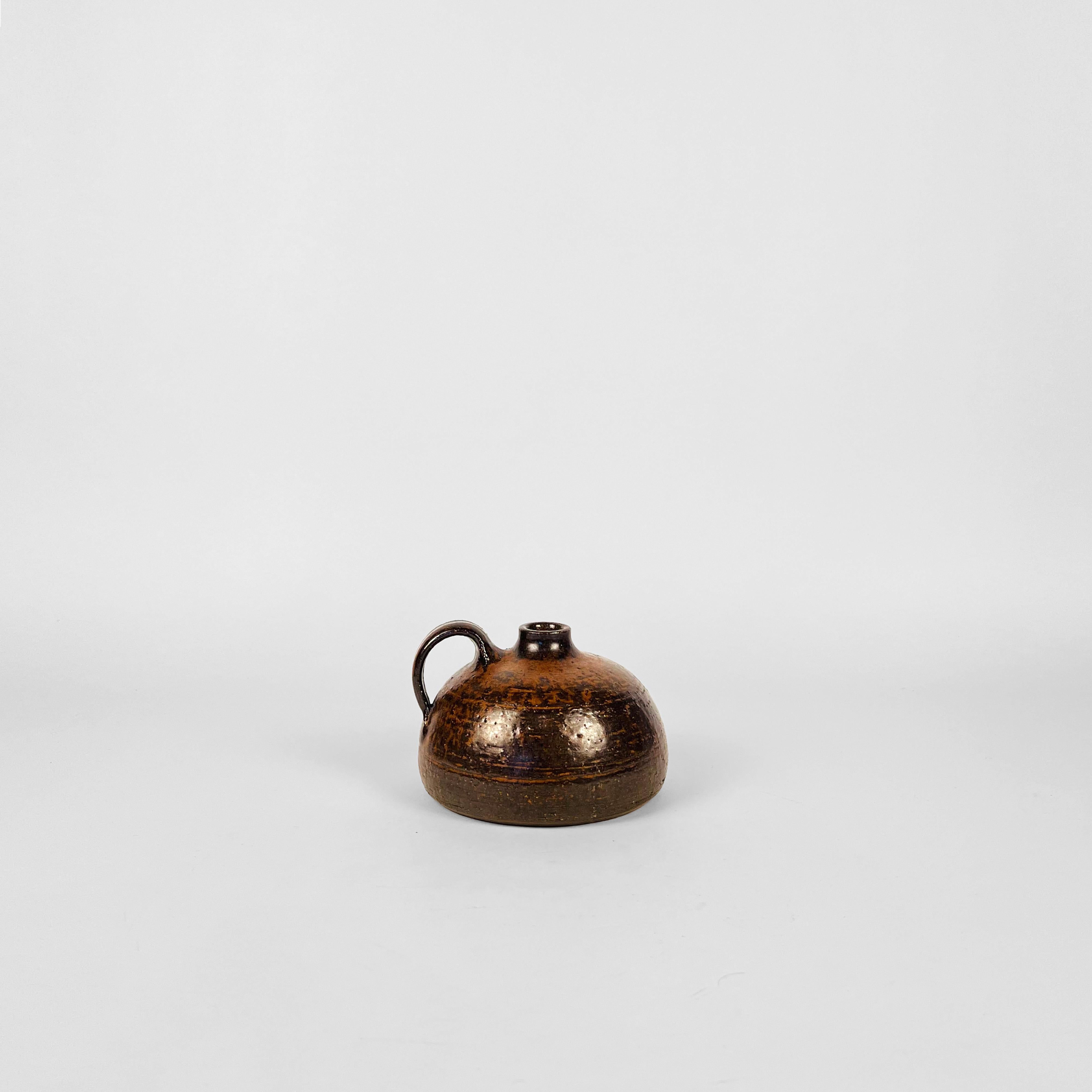 Jarrón de estudio con asa de mediados de siglo, Alemania Occidental, obra del famoso ceramista Rudi Stahl. Este jarrón también puede utilizarse como portavelas.
Acabado en tonos tierra claros texturizados con un toque de óxido.
Firmada a mano por el