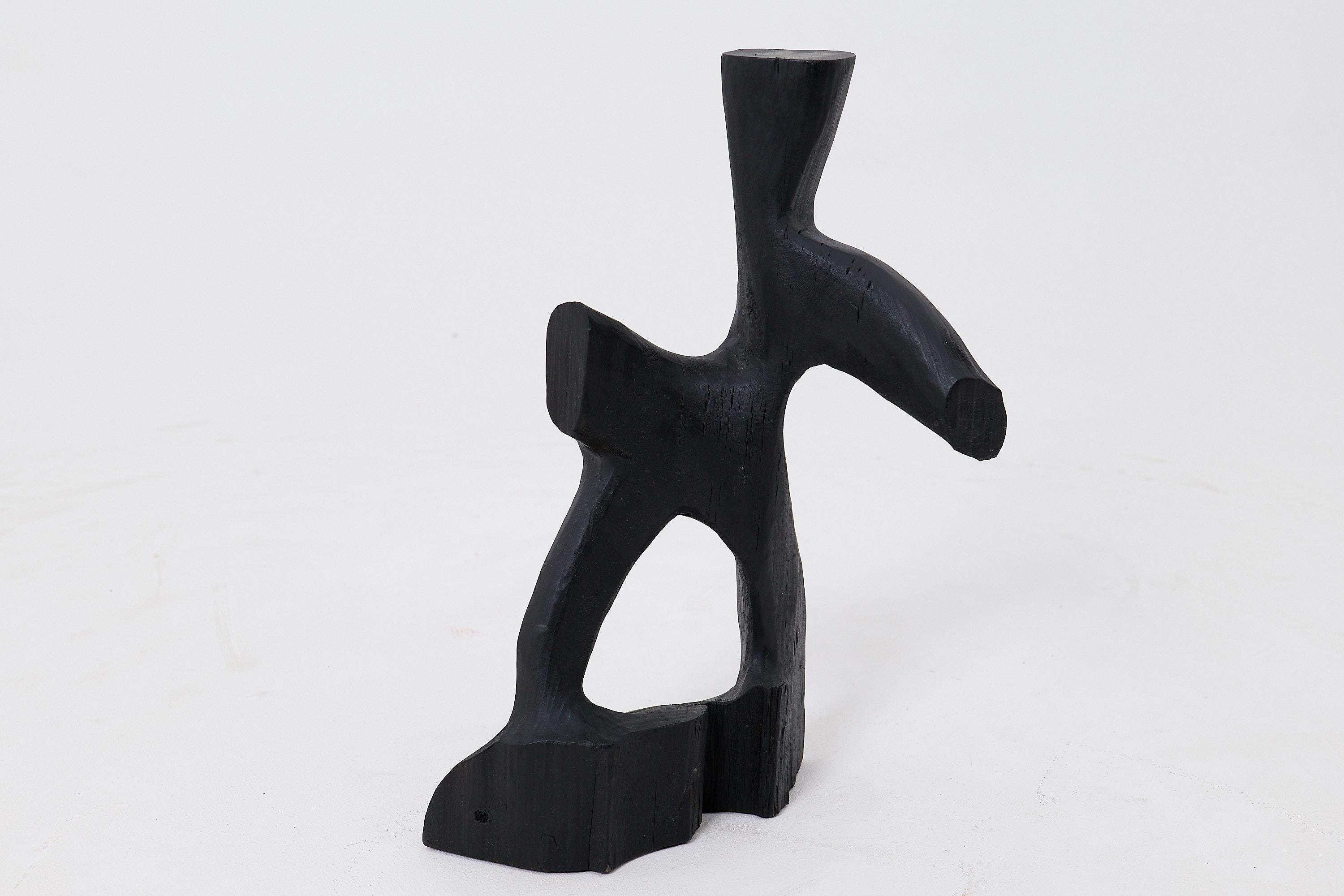This expressive abstract sculpture is a one of a kind piece, hand carved from a single block of solid hardwood. Its dynamic silhouette, defined by reaching limbs and an open stance, evokes a sense of captured movement, like a figure in motion or a
