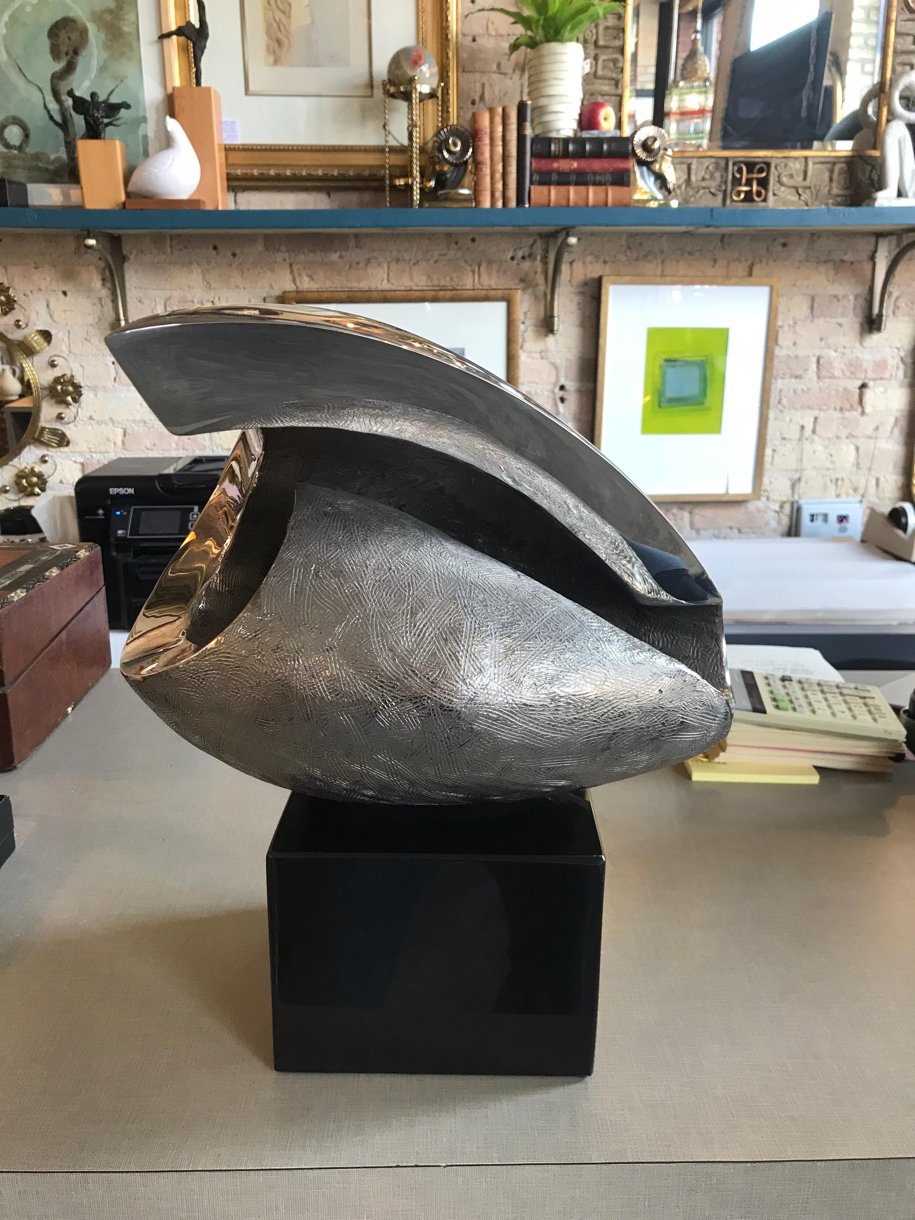 This is an abstract etched chrome sculpture by S.S. Barron the second in 1991 The sculpture is mounted on a metal stand that rotates to different positions. It is the first out of 9 made.