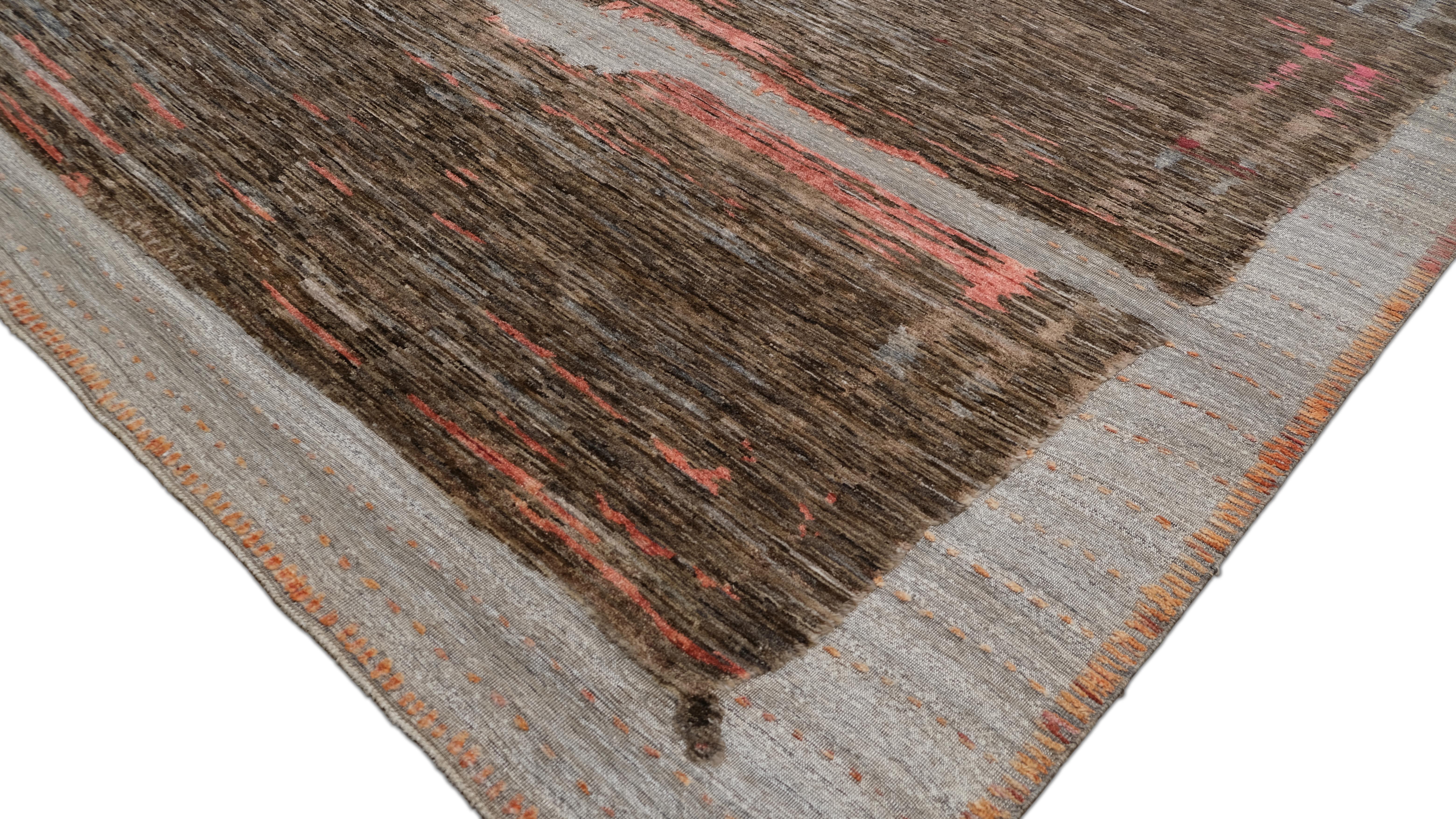 Introduce una atrevida declaración artística en tu espacio con esta alfombra de lana anudada a mano, con un moderno diseño abstracto de influencia tribal. La composición única muestra una interacción de tonos terrosos, que mezclan el marrón intenso,