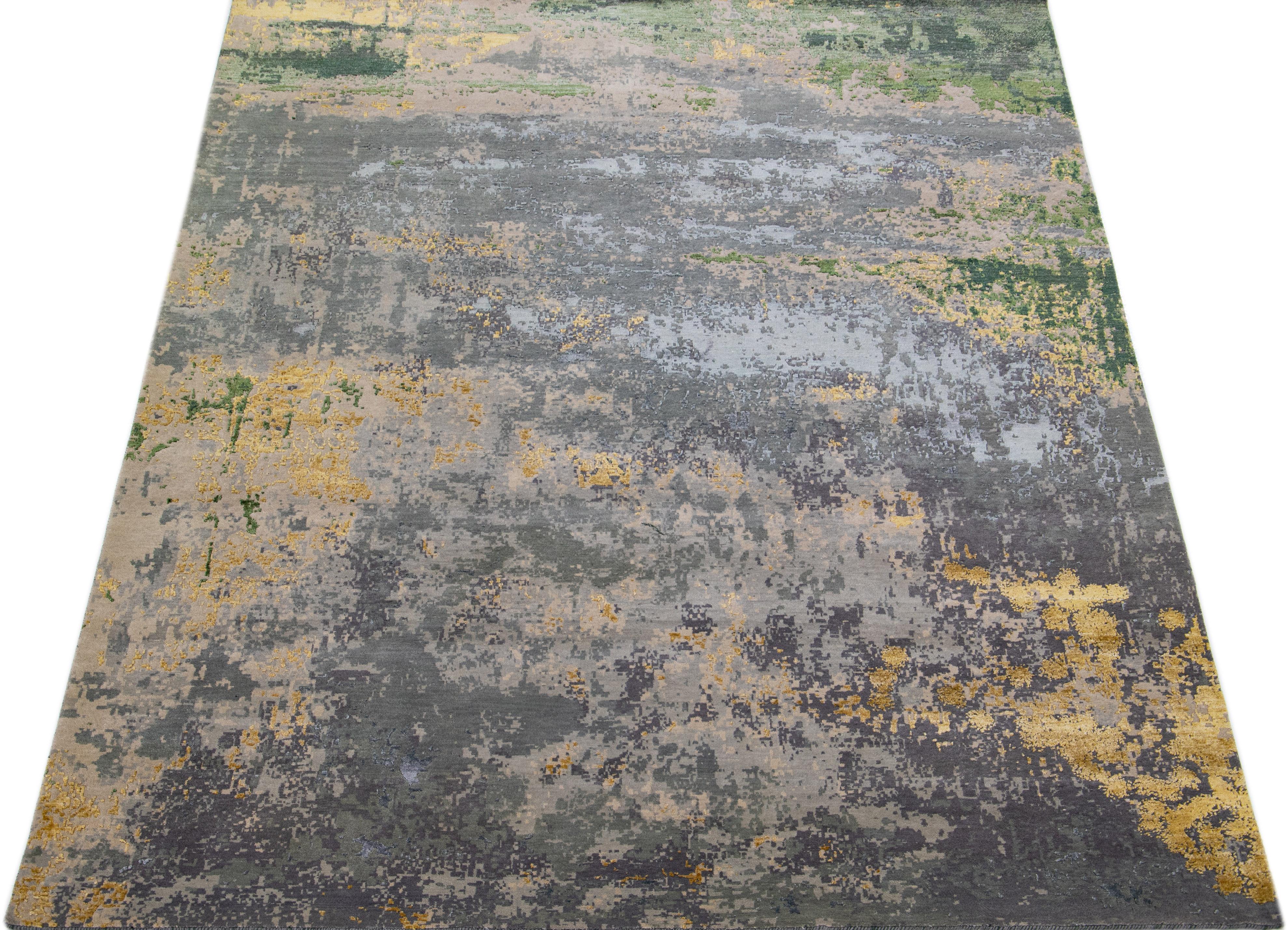 This Indian wool and silk blend rug features a gray field with an abstract pattern detailing golden and green colors. Its composed materials provide robustness and longevity, while its ornamental design infuses any room with sophistication.

This