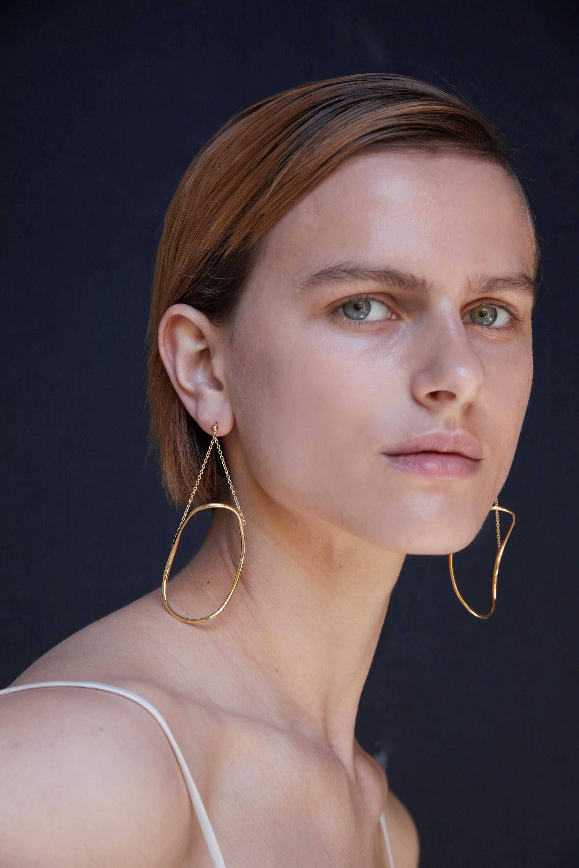 BAR Jewellery, London UK, GLIDE EARRINGS, Gold Plated 

The Glide Earrings are abstract hoops that dance beneath the ear. Inspired by the work of Constantin Brancusi and Barbara Hepworth, whose considered, curved sculptures mimic forms in
