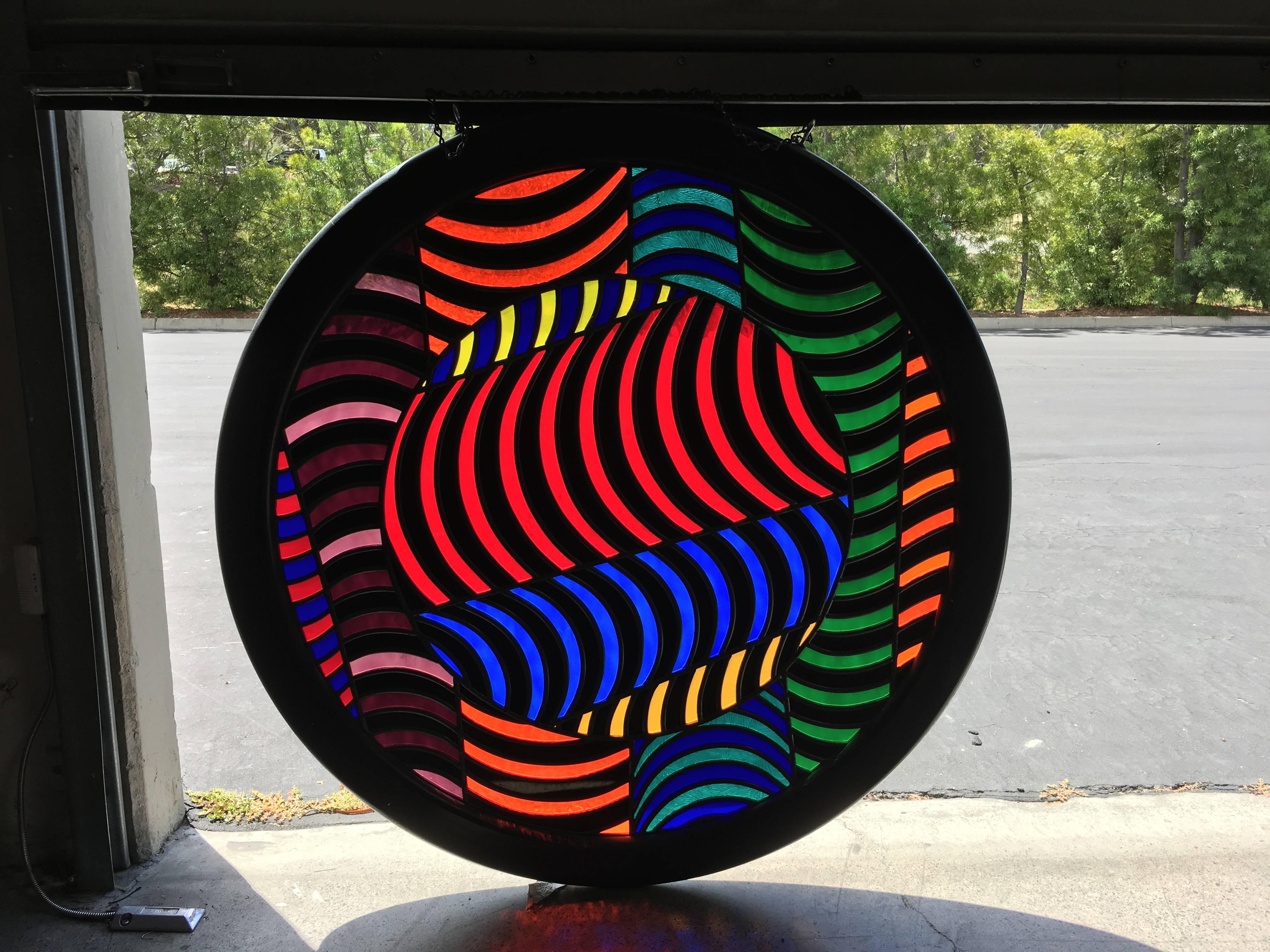 Round abstract design stained glass window in a ebonized oak frame.