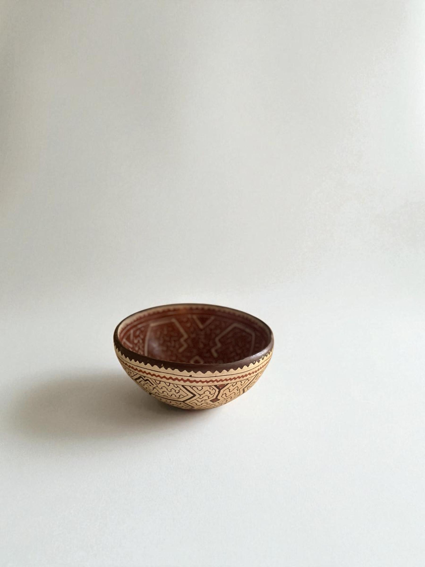 Abstrakte Schale aus peruanischer Töpferware. Rote Hintergrundfarbe und schwarze geometrische Muster. 

Durchmesser: 8,5