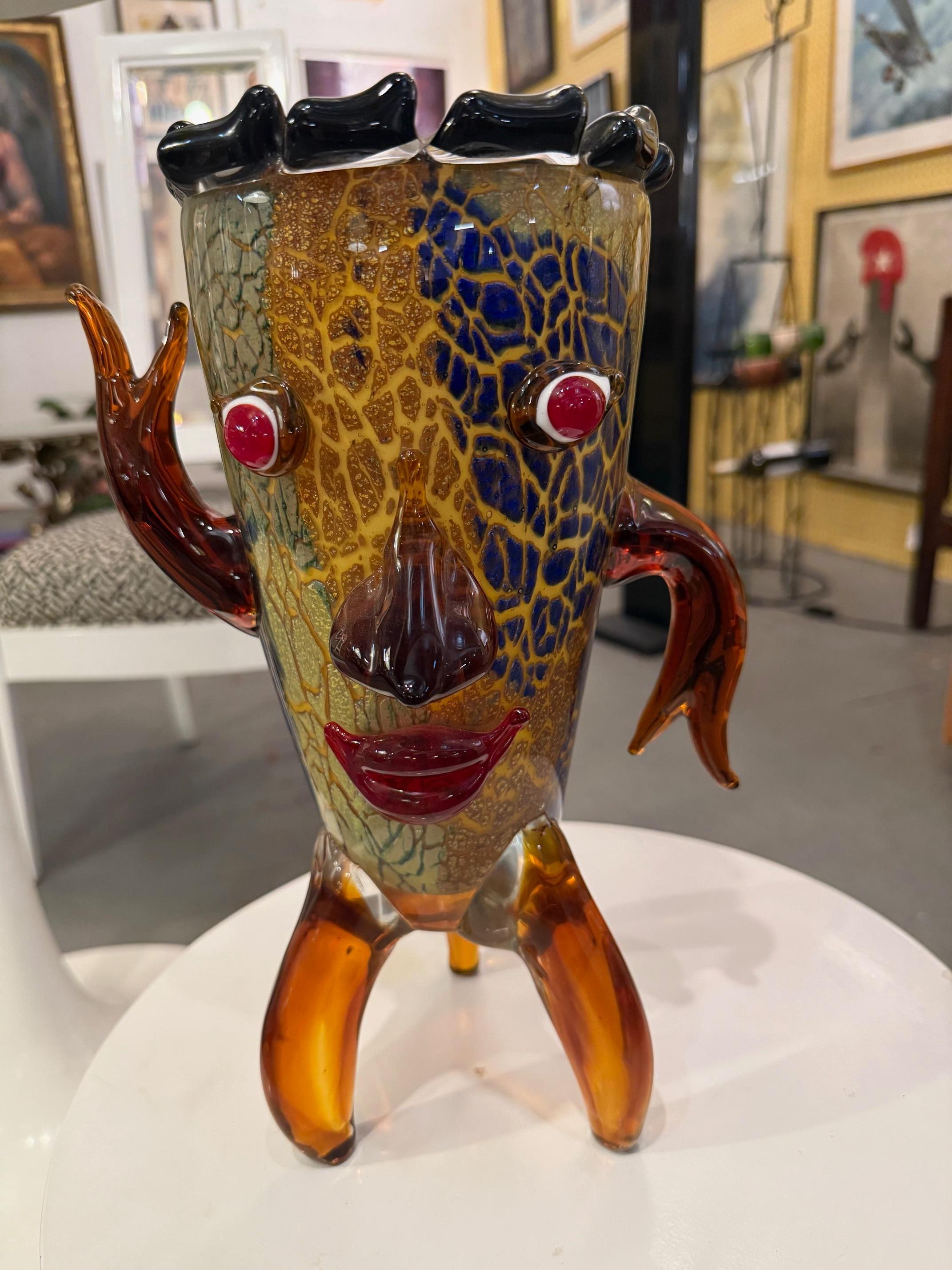 Fantaisiste et audacieuse, cette sculpture en verre fabriquée à la main capture l'énergie joyeuse de l'art du verre italien du milieu du siècle dernier. Le visage du personnage, composé de lèvres rouges expressives, de bras levés et de traits