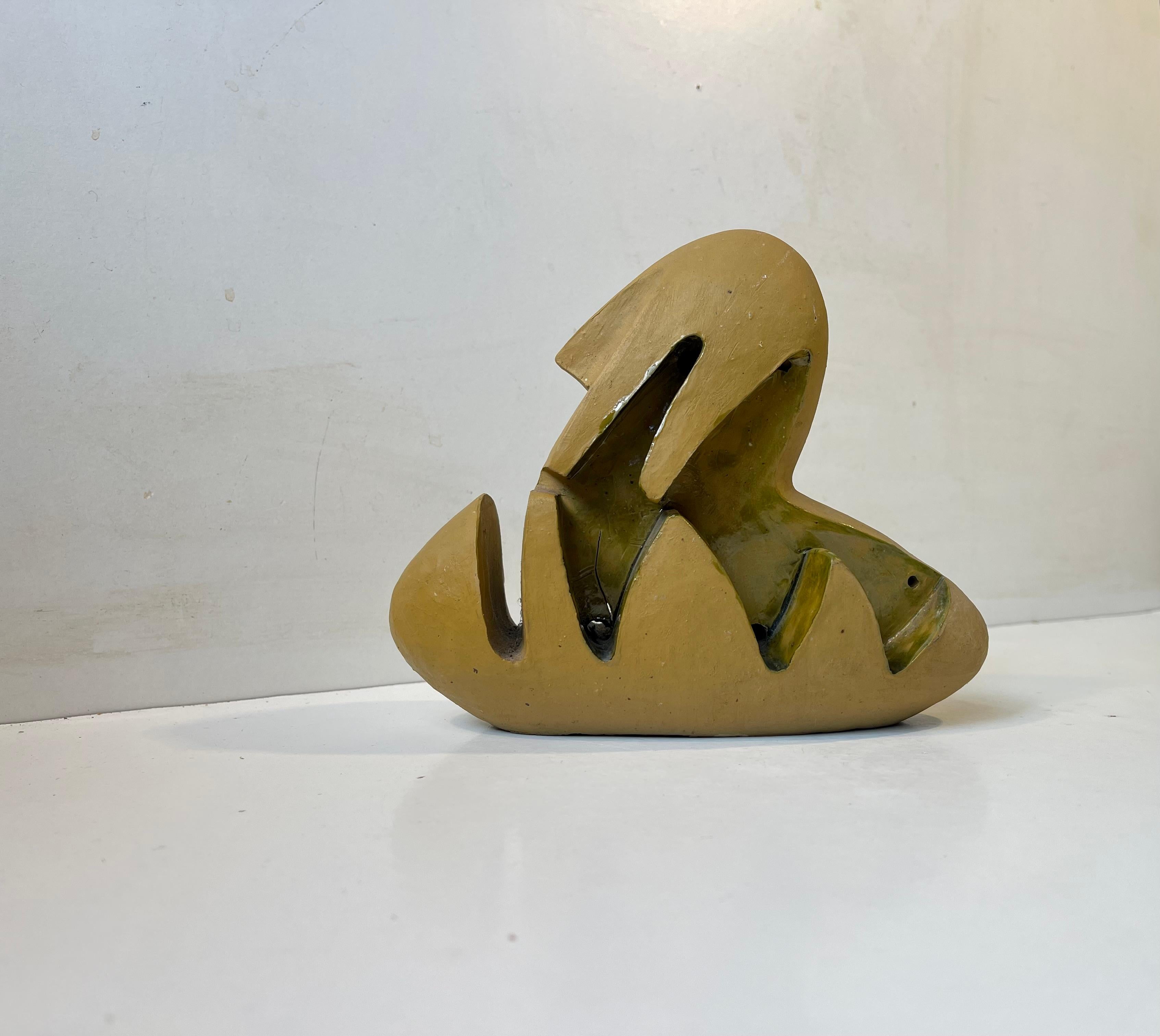 A 1960s sculptural surrealist figurine/ornament in partially glazed and hand-painted ceramic. An abstract form based upon an ovoid main shape. The main color is mustard and the applied glaze olive/pickle in tonality.  Uniquely made by the Danish
