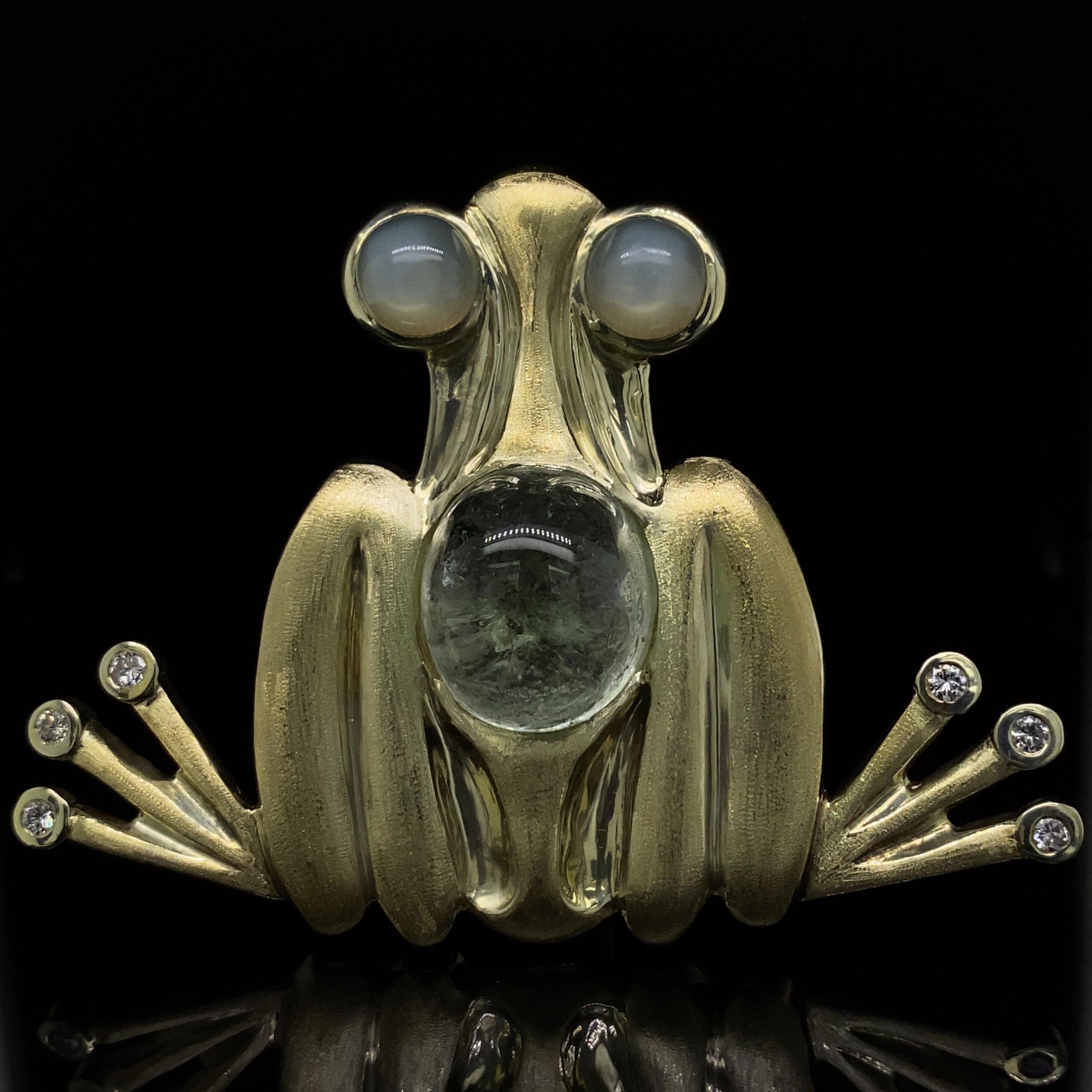 This heavy, unusual and graphic 18 karat yellow gold frog brooch has moonstone eyes, a tourmaline back, diamond toes and a soft, shimmery matte satin finish. 

The six diamonds are nice and bright bezel-set brilliant cuts.  We rate them G-H color
