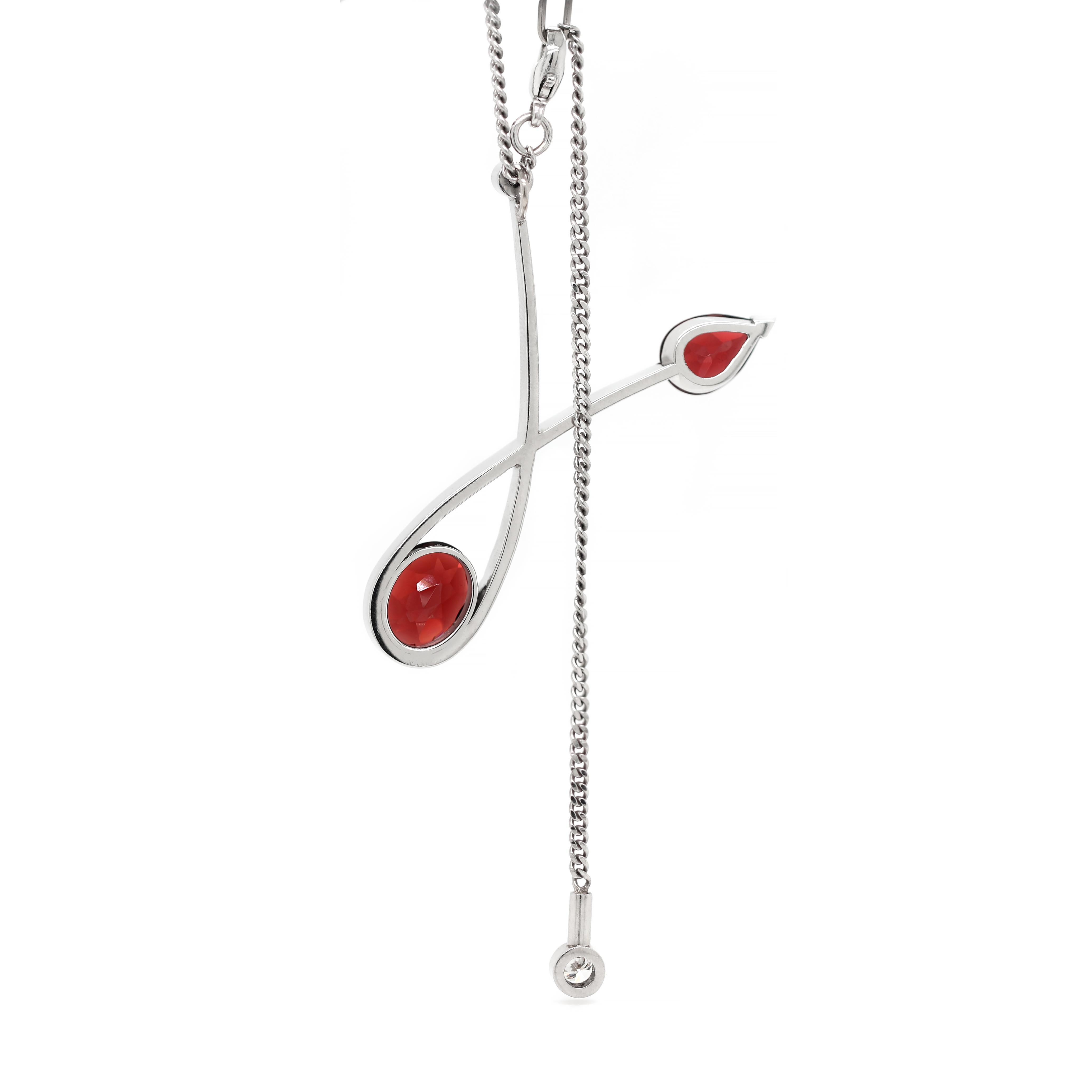 This lovely hand made necklace features an abstract loop platinum pendant, set with a pear shaped and an oval dark red garnet, coming to a combined approximate weight of 5.16 carats and a round brilliant cut diamond, weighting approximately 0.15ct.