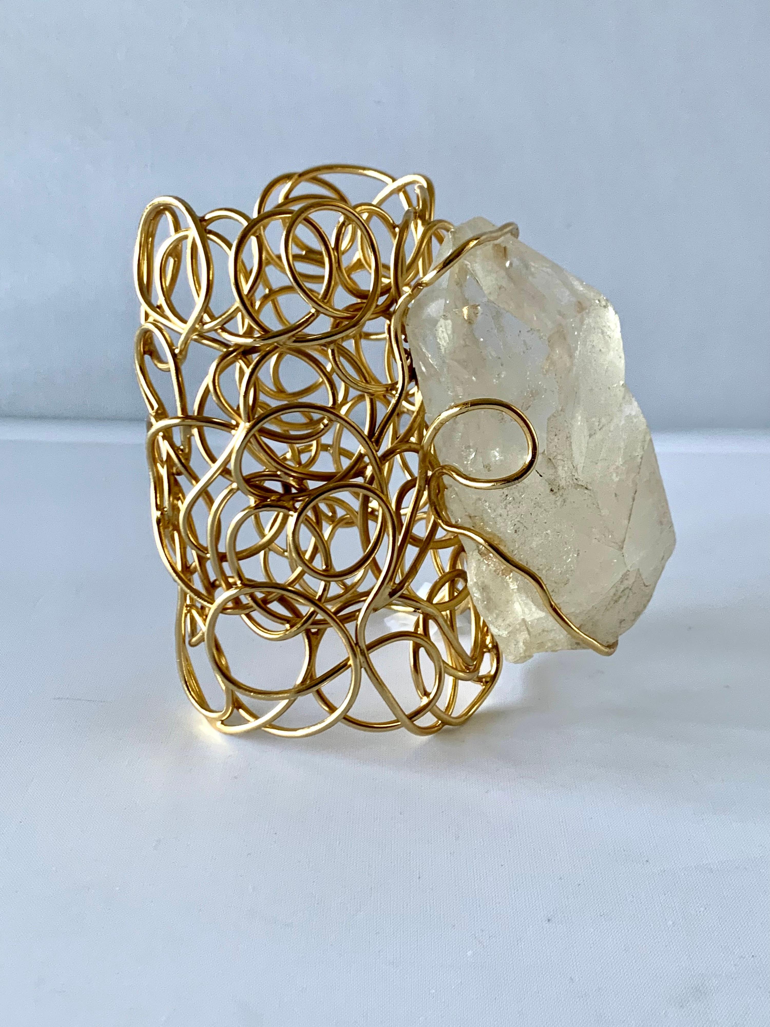 Massive gilt rock crystal cuff bracelet, crafted from hand-manipulated gilded brass featuring an abstract design and embellished by a large piece of faceted rock crystal. Made in Paris France.

The bracelet has the romantic essence of Rober