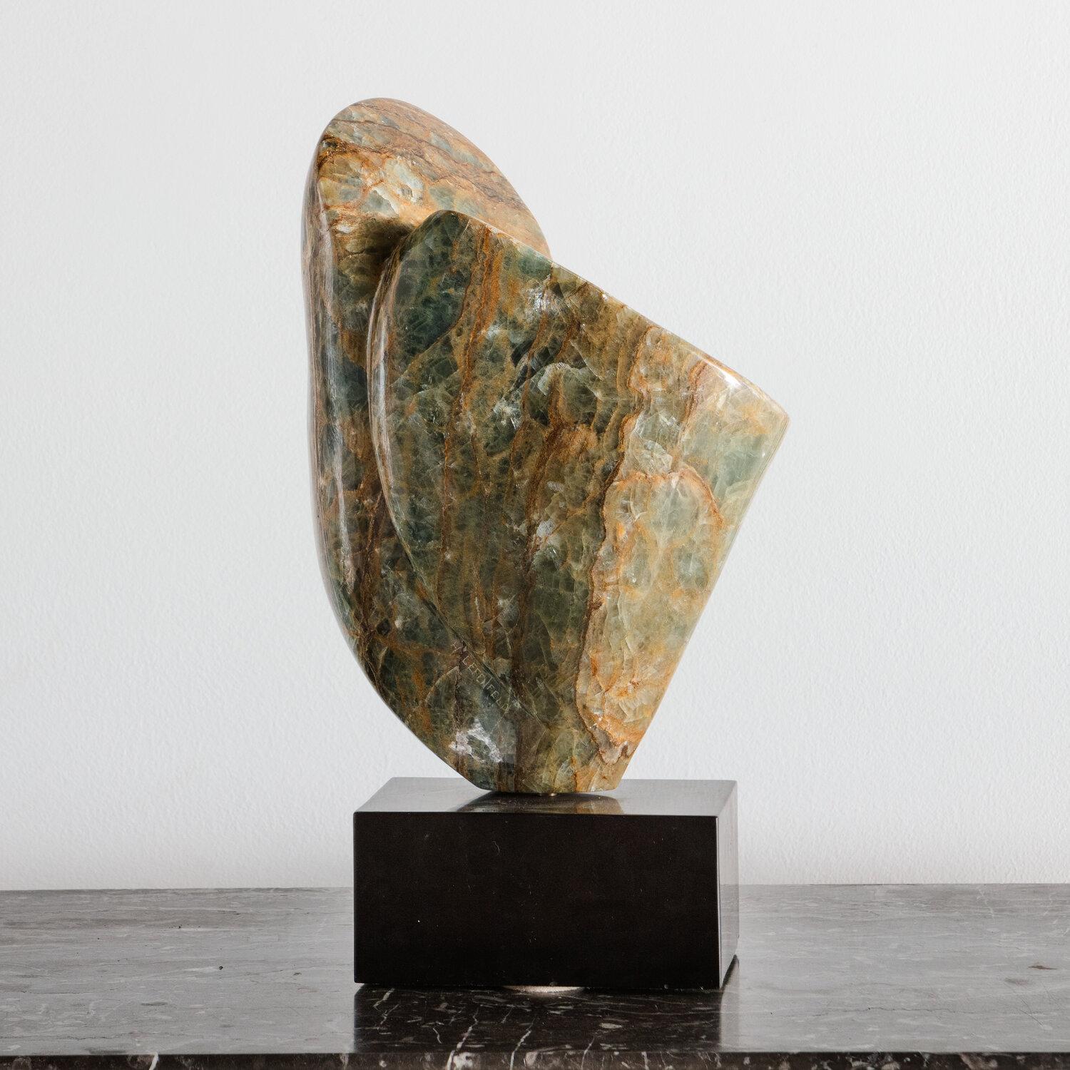 We lovingly sourced this sculpture while on a buying trip in Palm Beach, Florida. This beautiful sculpture is hand carved of a gorgeous green stone that features rust hued graining. It is mounted (and swivels) on a black stone base. It is signed “H.