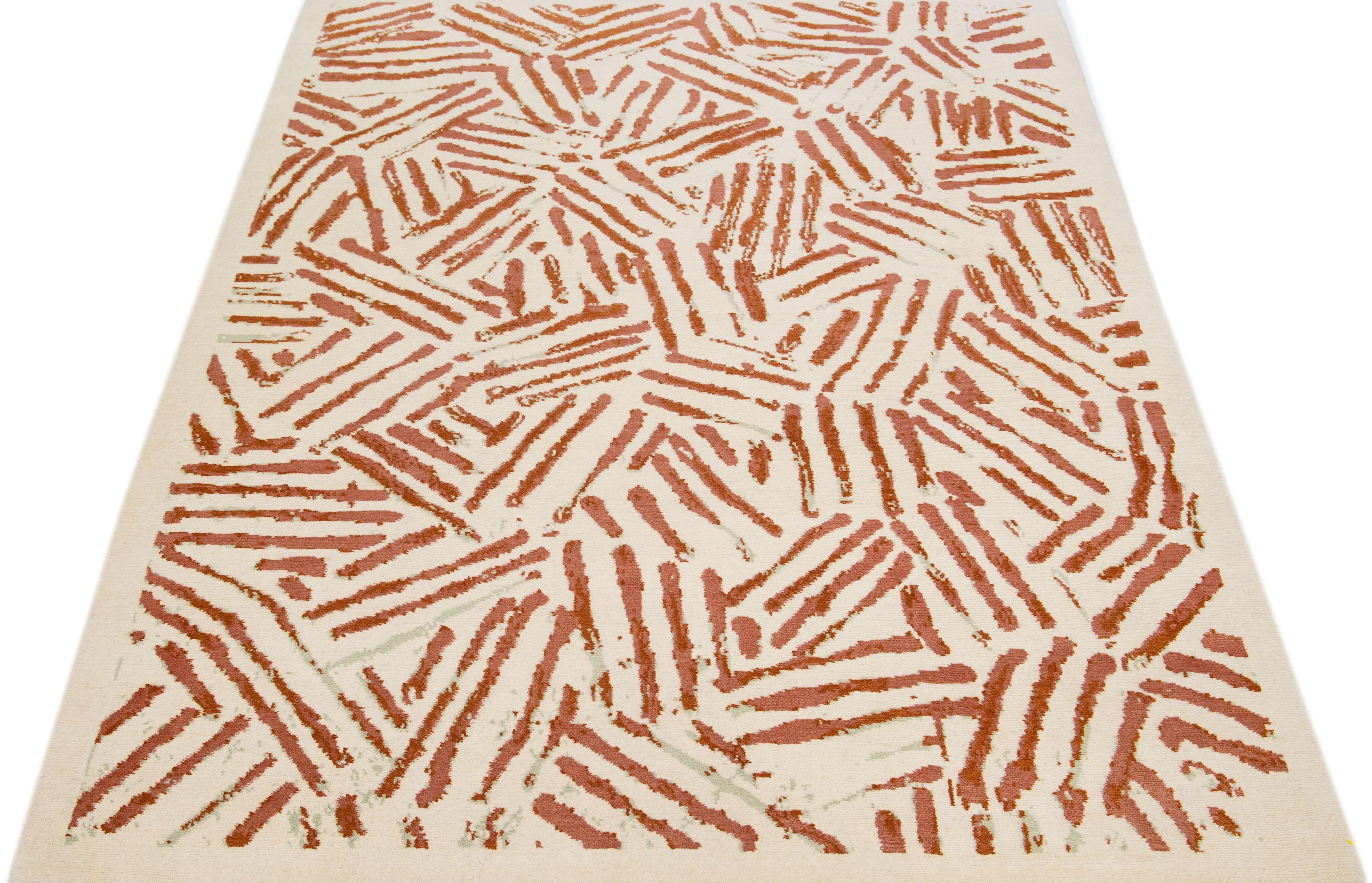 Ce tapis tibétain arbore un design abstrait contemporain en laine de haute qualité, nouée à la main à la perfection. La toile de fond ivoire présente un motif géométrique saisissant, accentué par des touches de couleur rouille pour plus de richesse