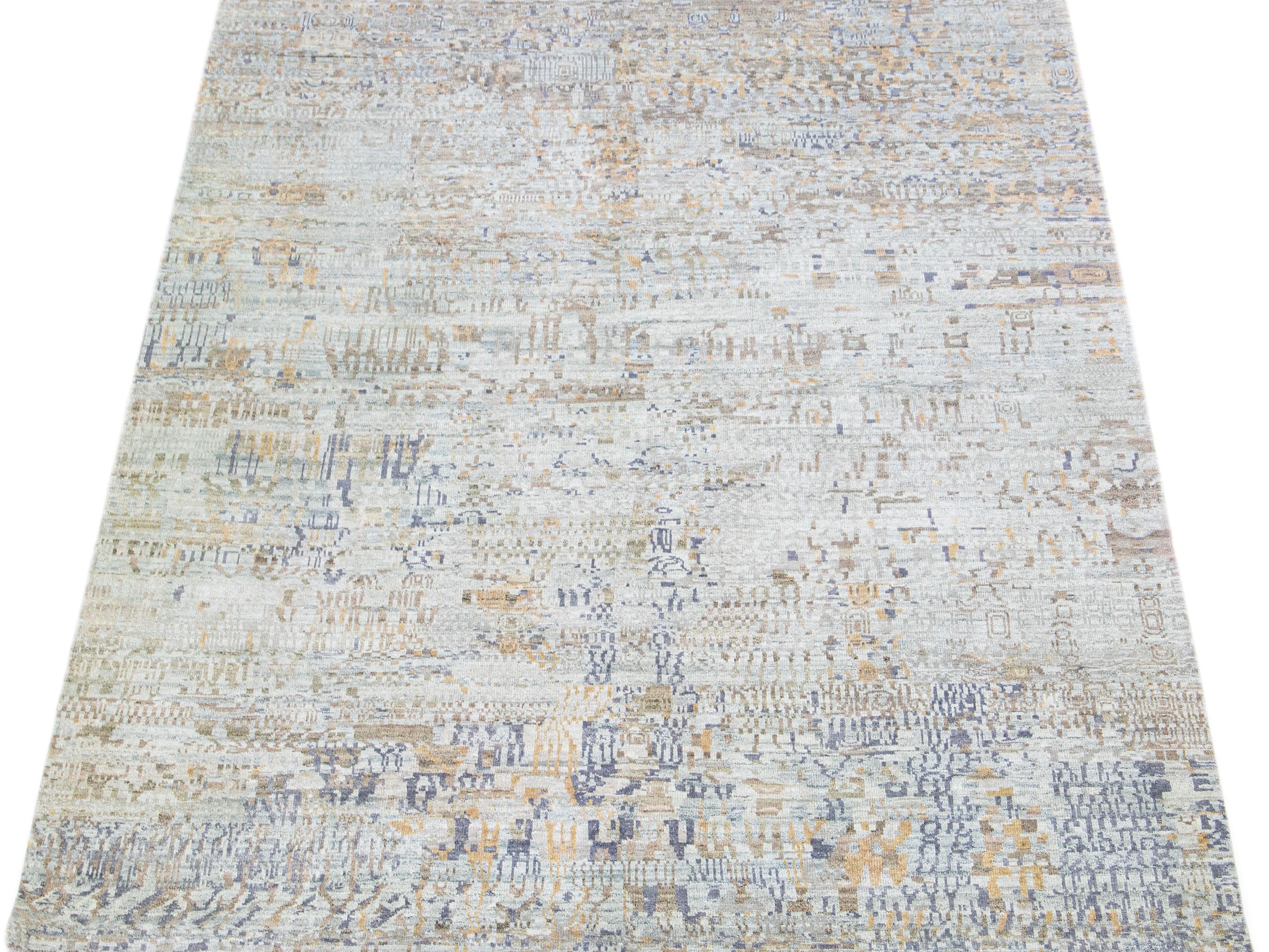 The contemporary design of this wool and silk rug showcases an enthralling tribal motif in a delicate grey shade. The tan accents uniquely enhance the abstract pattern.

This rug measures 7'10