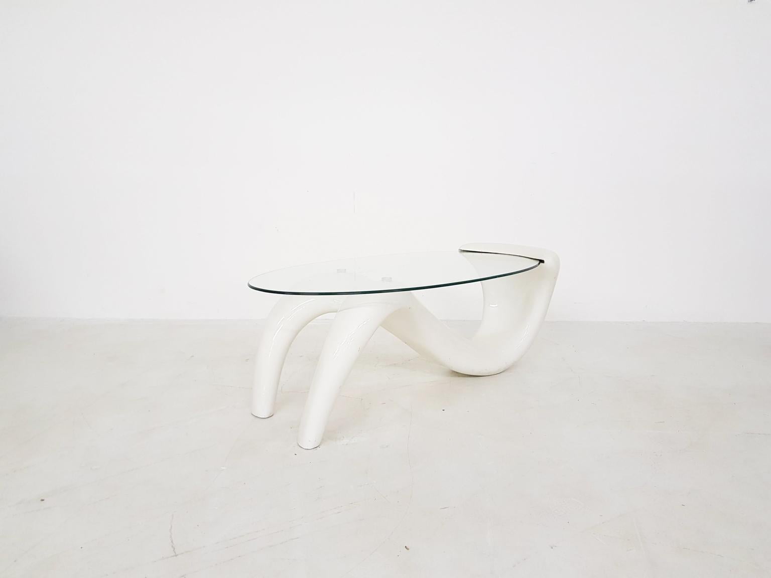 An elegant piece of art from the midcentury. This coffee table is shaped like an abstract human being holding the oval glass top on his or her knees and torso.

We haven't found the designer yet, but we sure see this item as a piece of art. A