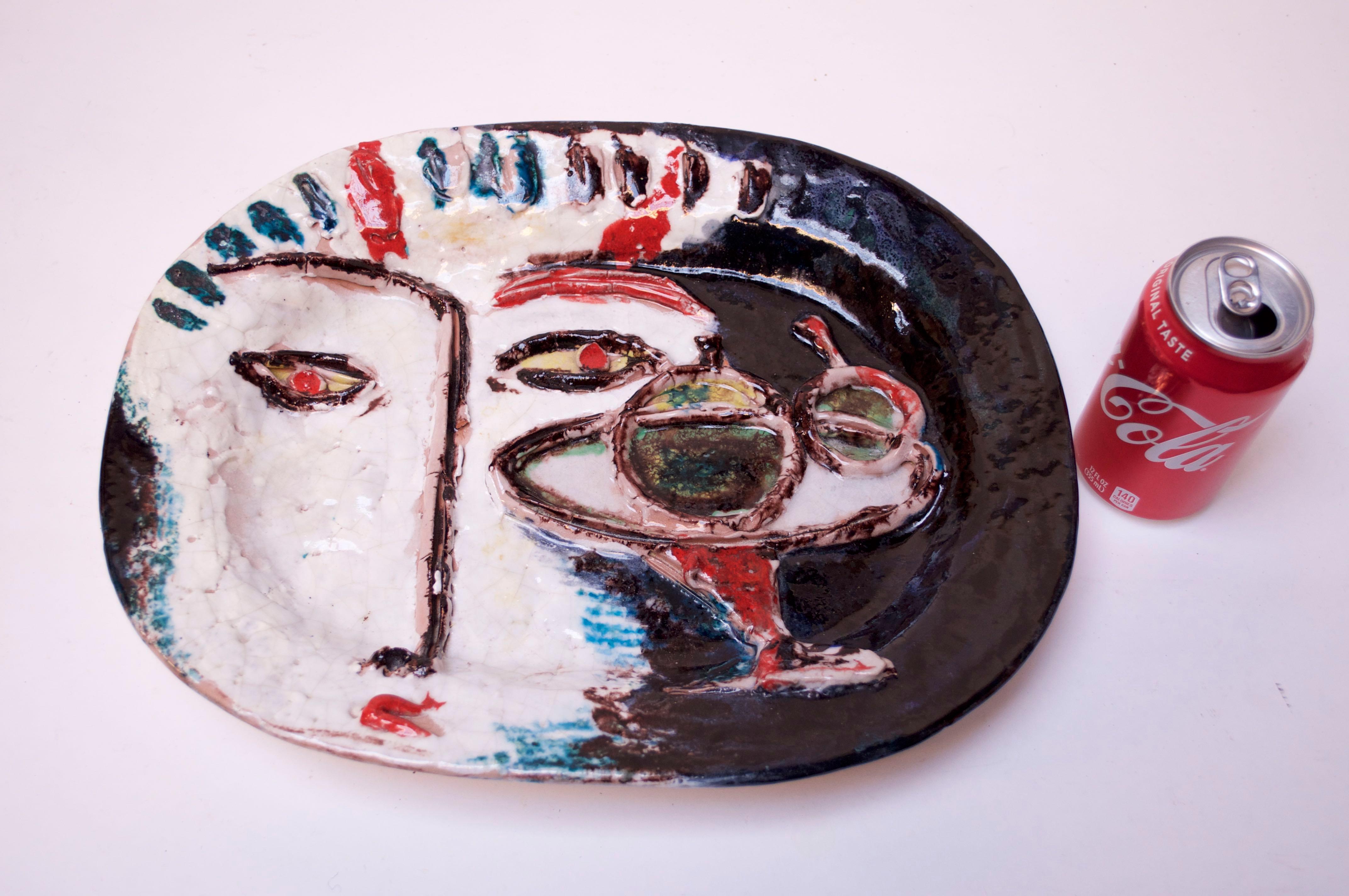 Masterful, large Italian ceramic charger depicting an abstract face with martini. Bold colors and a combination of both flat hand painted and raised decoration give the piece added depth / dimension. There appears to be minor loss to the bridge of