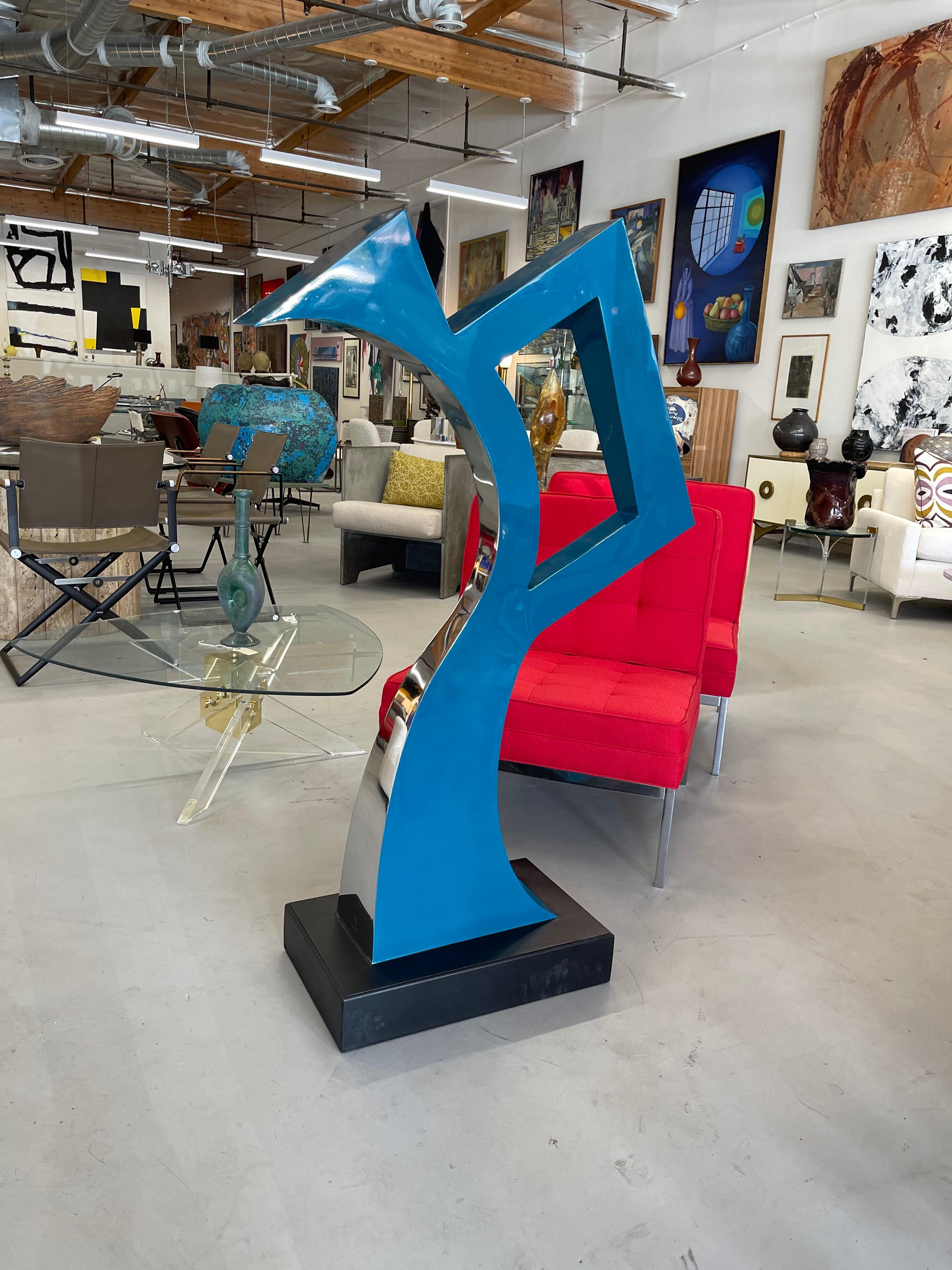 A wonderful large abstract steel sculpture by a talented pair local Palm Springs, the Sutton Brothers. It is painted and finished on one side in polished steel. Great presence. The platform base is painted a flat black. The base is intentionally