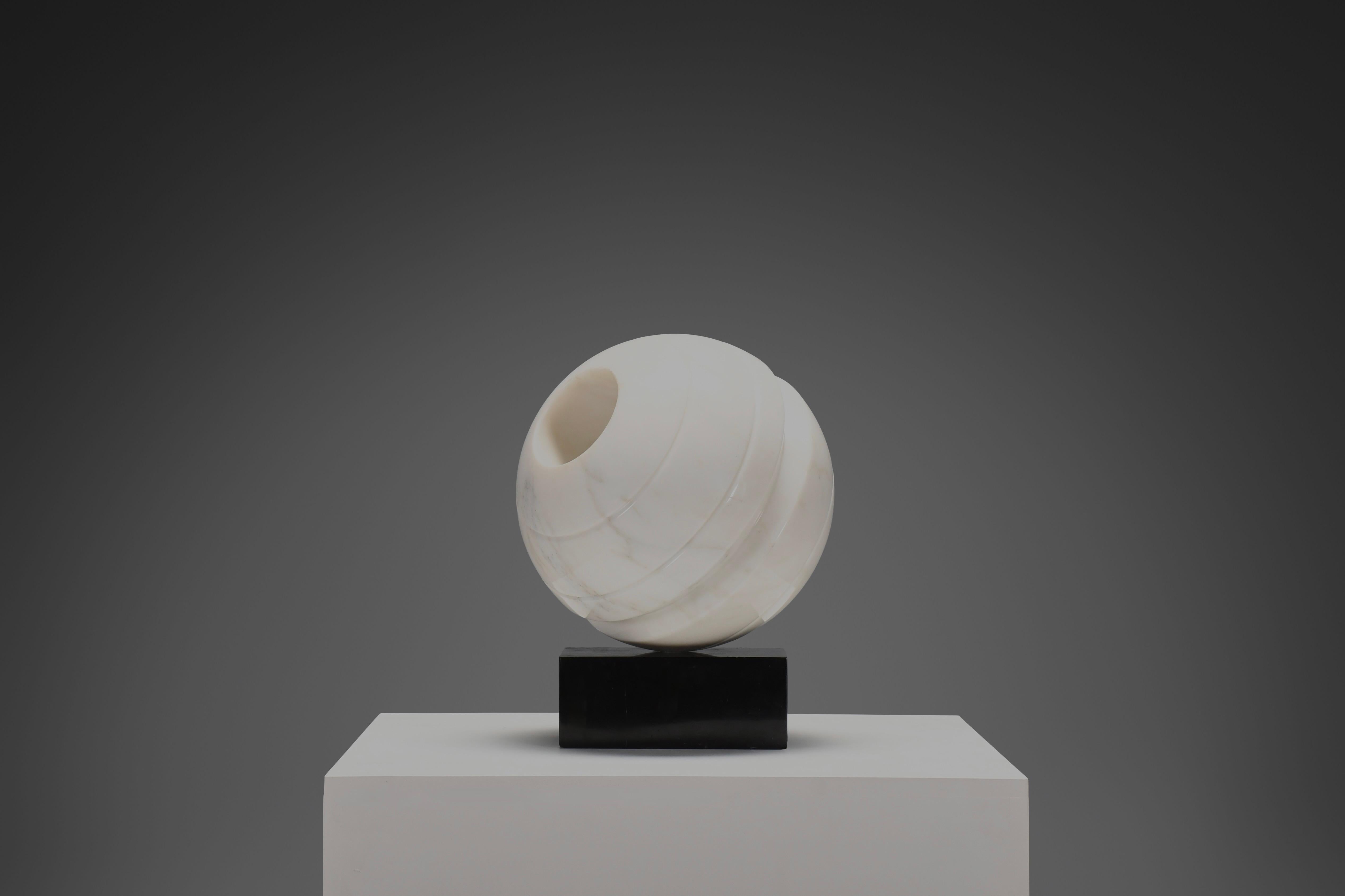 This refined marble sculpture by Italian artist Aldo Dazzi embodies the harmonious balance between geometry and organic form characteristic of Carrara’s modern sculptural tradition.

Carved from a single block of white Carrara marble, the sphere