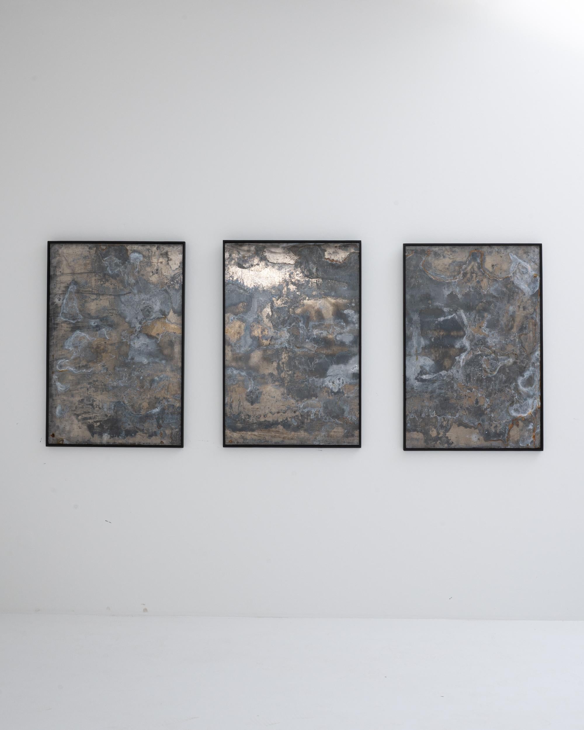 Bold and enigmatic, this large scale abstract triptych combines the hand of man and the hand of nature. The form has a Minimalist simplicity: three sheets of metal are set within black wooden frames. The surface of the metal combines human