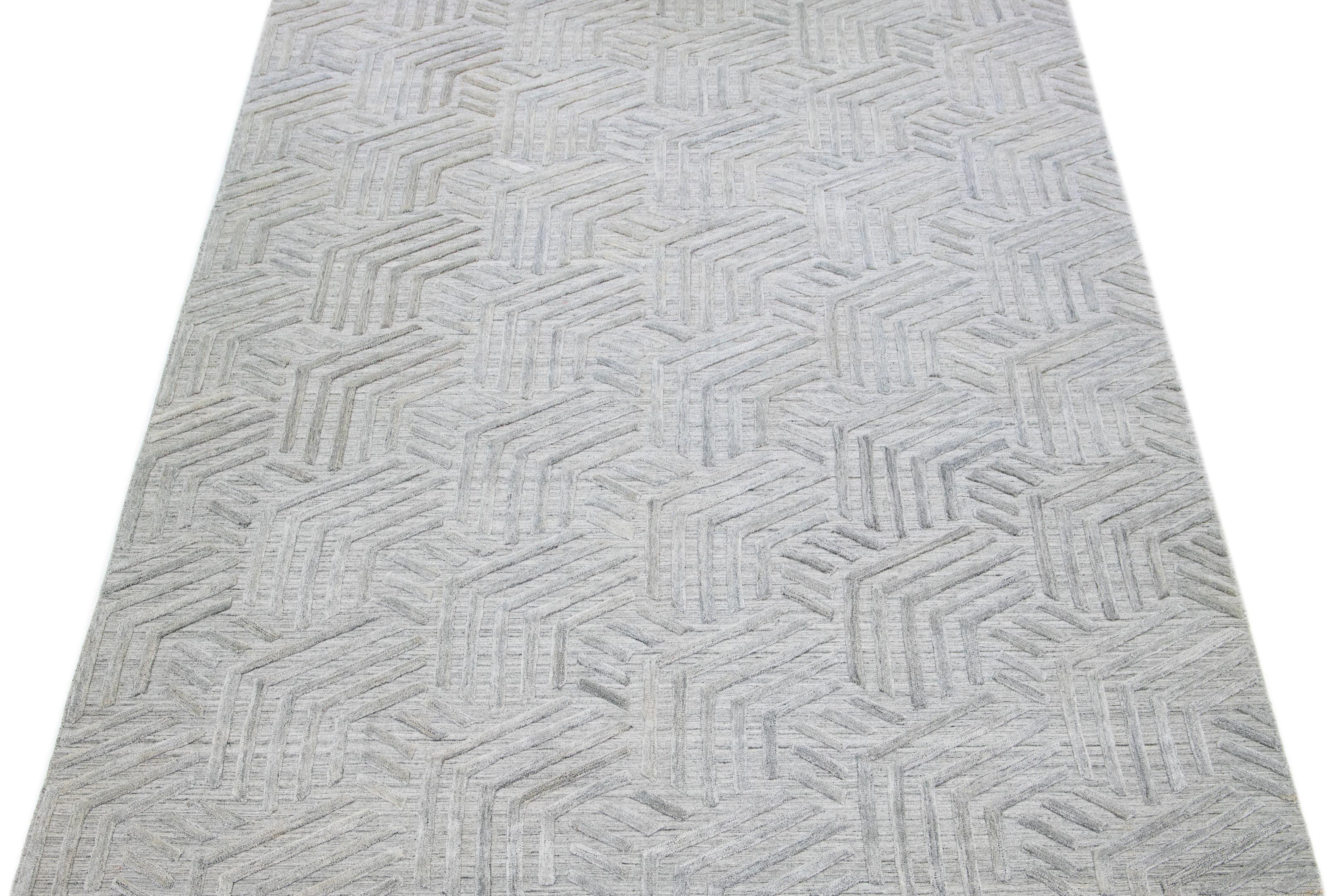 Découvrez la beauté d'un tapis moderne indien transitionnel en laine tissée à plat et nouée à la main, avec un champ gris sophistiqué. Le motif géométrique ivoire, texturé et gracieux, qui parcourt l'ensemble du tapis, ajoute à son charme
