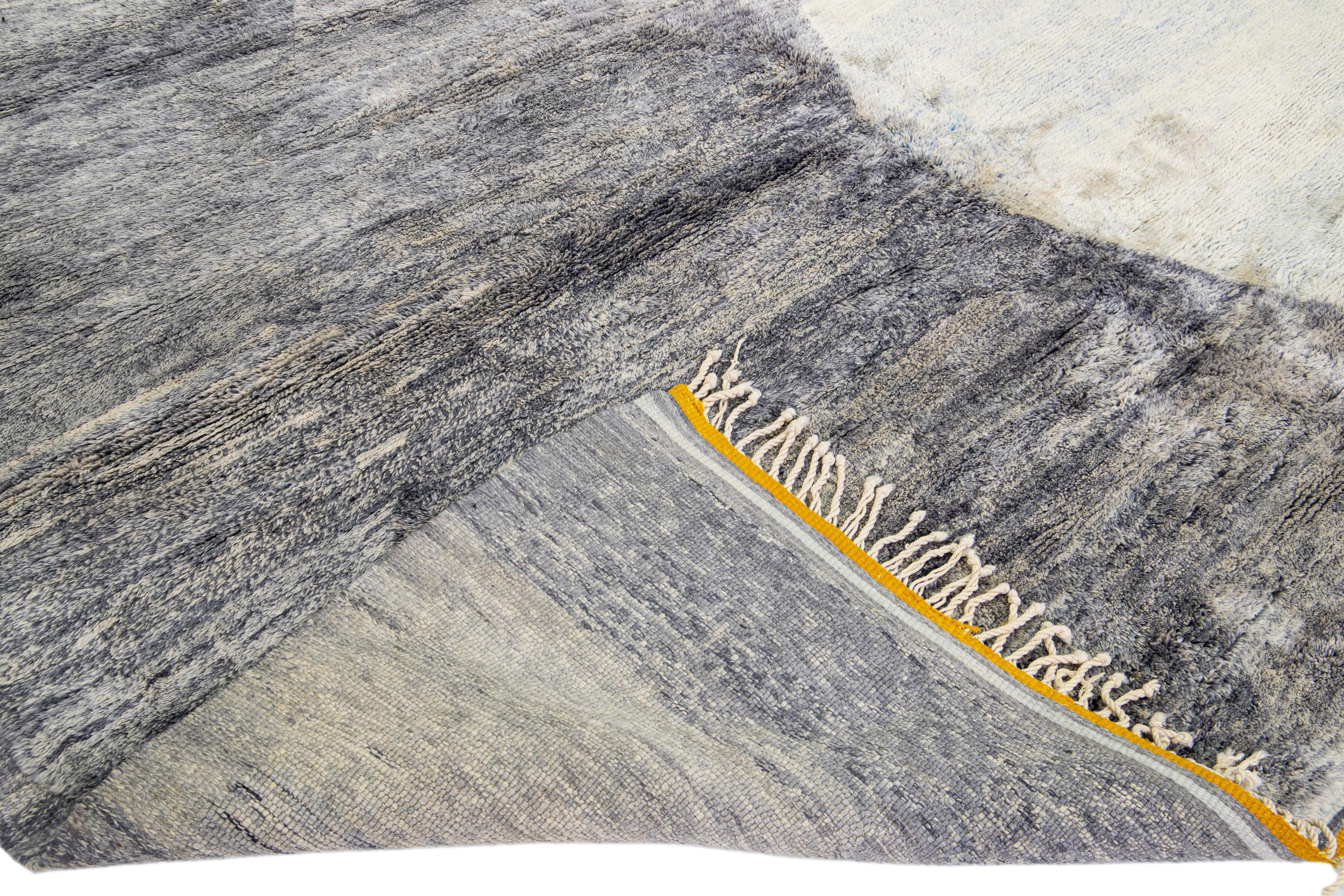 Magnifique tapis marocain en laine noué à la main avec un champ gris. Ce tapis moderne a une couleur d'accent jaune et des franges beiges dans un magnifique design abstrait.

Ce tapis mesure : 11' x 14'.

Nos tapis sont nettoyés par des