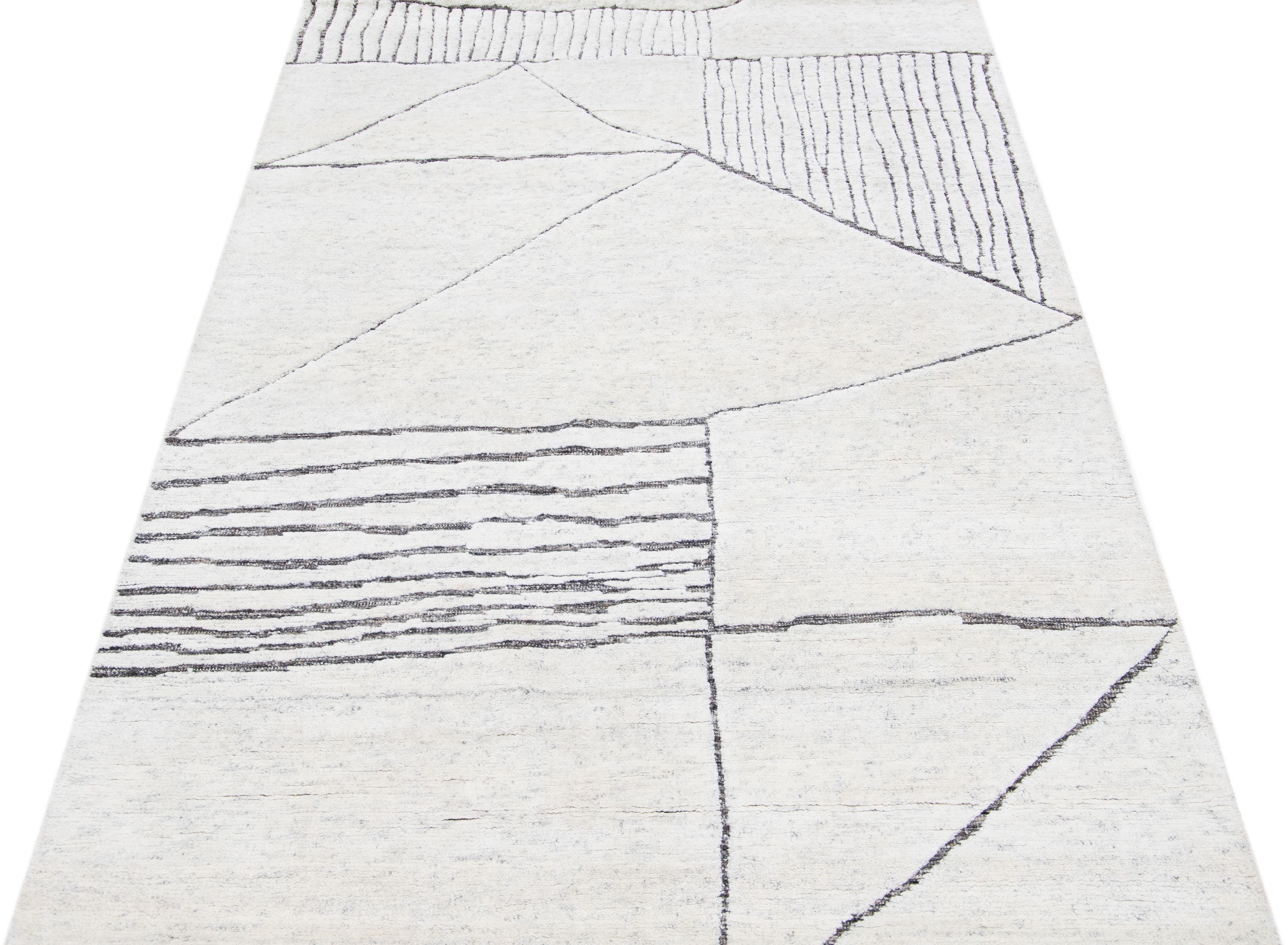 Beautiful modern Moroccan-style hand-knotted wool rug with an ivory color field. This rug is part of our Apadana's Safi Collection and features a minimalist design in gray.

This rug measures: 5' x 7'11