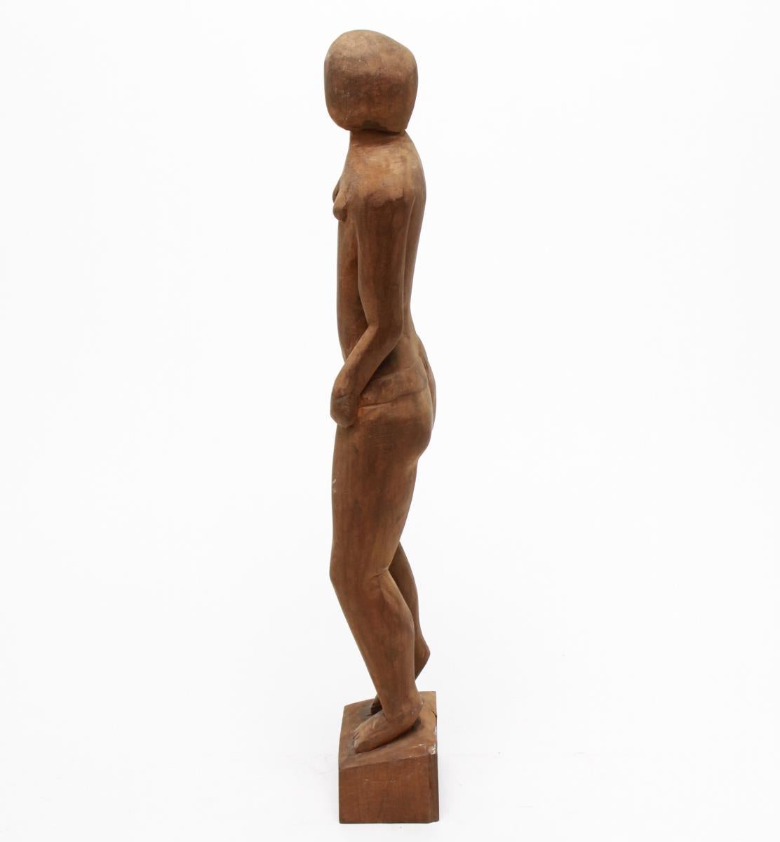 Abstract modern carved wood sculpture of a standing female nude, the underside with a carved signature 'Ney'. The piece is lacking its proper right arm at the height of the elbow, with the remnant of the hand still attached to face.