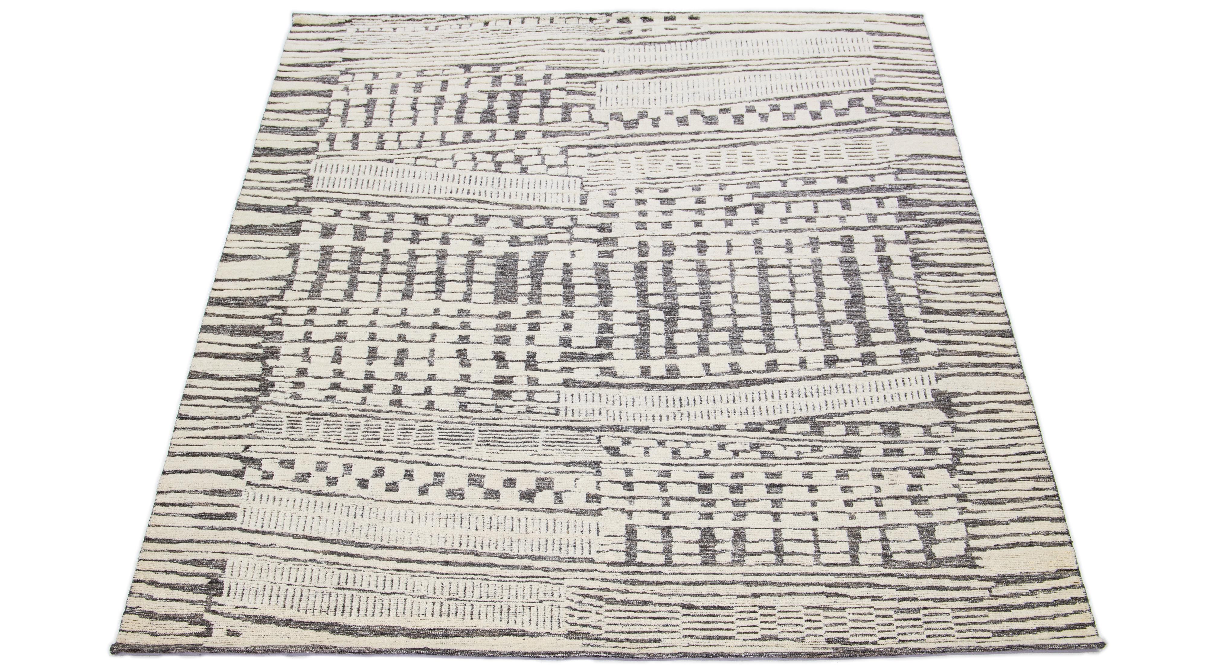 This hand-knotted wool rug showcases a modern Moroccan-inspired motif highlighting understated beige hues against a bold gray foundation, creating a captivating abstract Design.

This rug measures 8'2