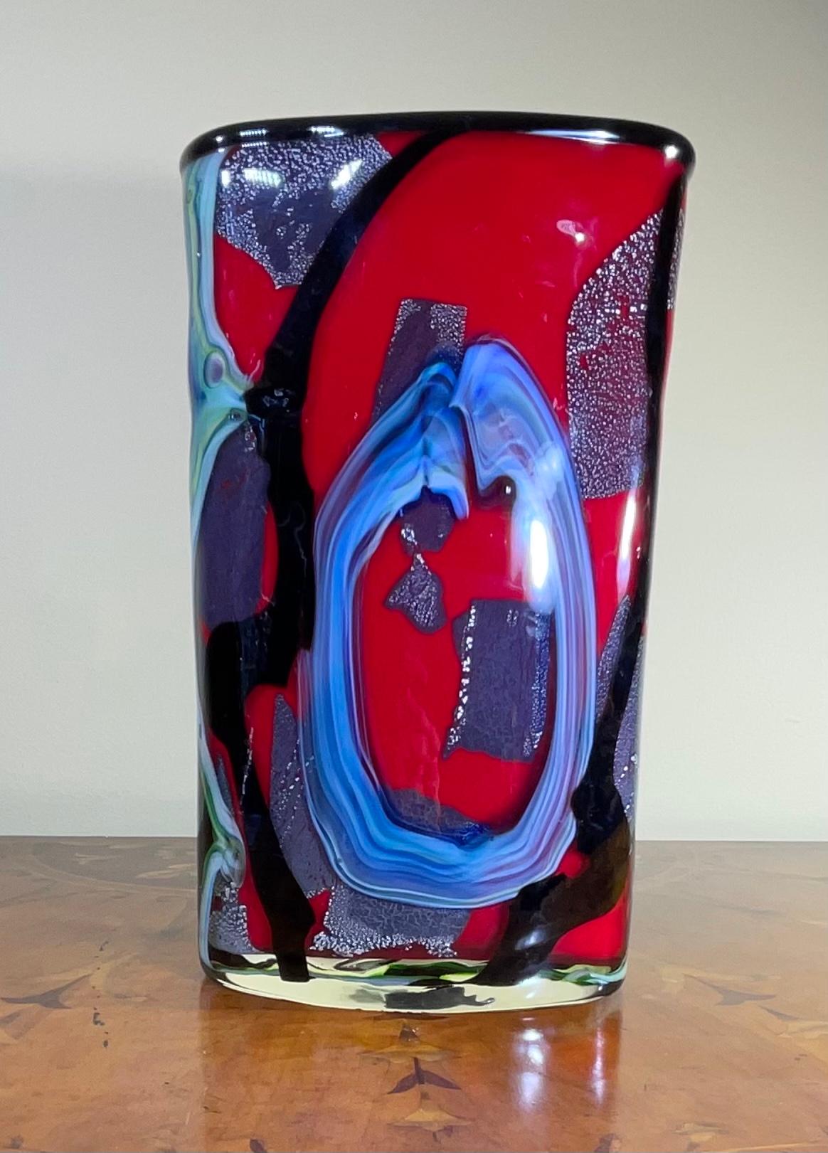 Elegant vase hand blown Studio Murano glass, to characterize the uniqueness of the vibrant colors of garish-blue, red and green embellished with the use of silver dust, which creates a suggestive texture of shapes and colors, all in abstract