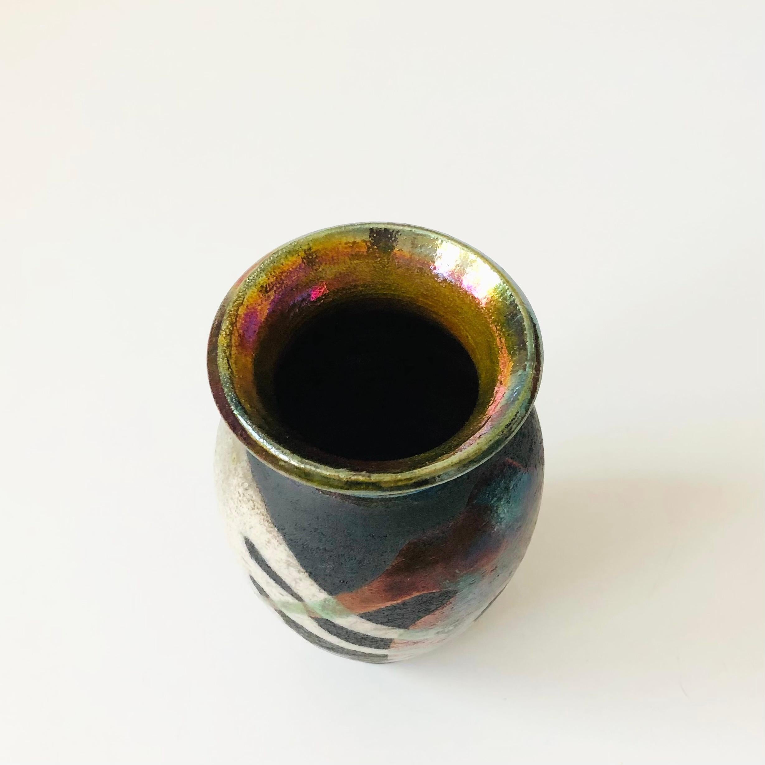 Un magnifique vase vintage en poterie raku. Magnifique couleur de base foncée avec des glaçures multicolores en goutte-à-goutte dans un motif abstrait de forme libre. Signé sur la base.
