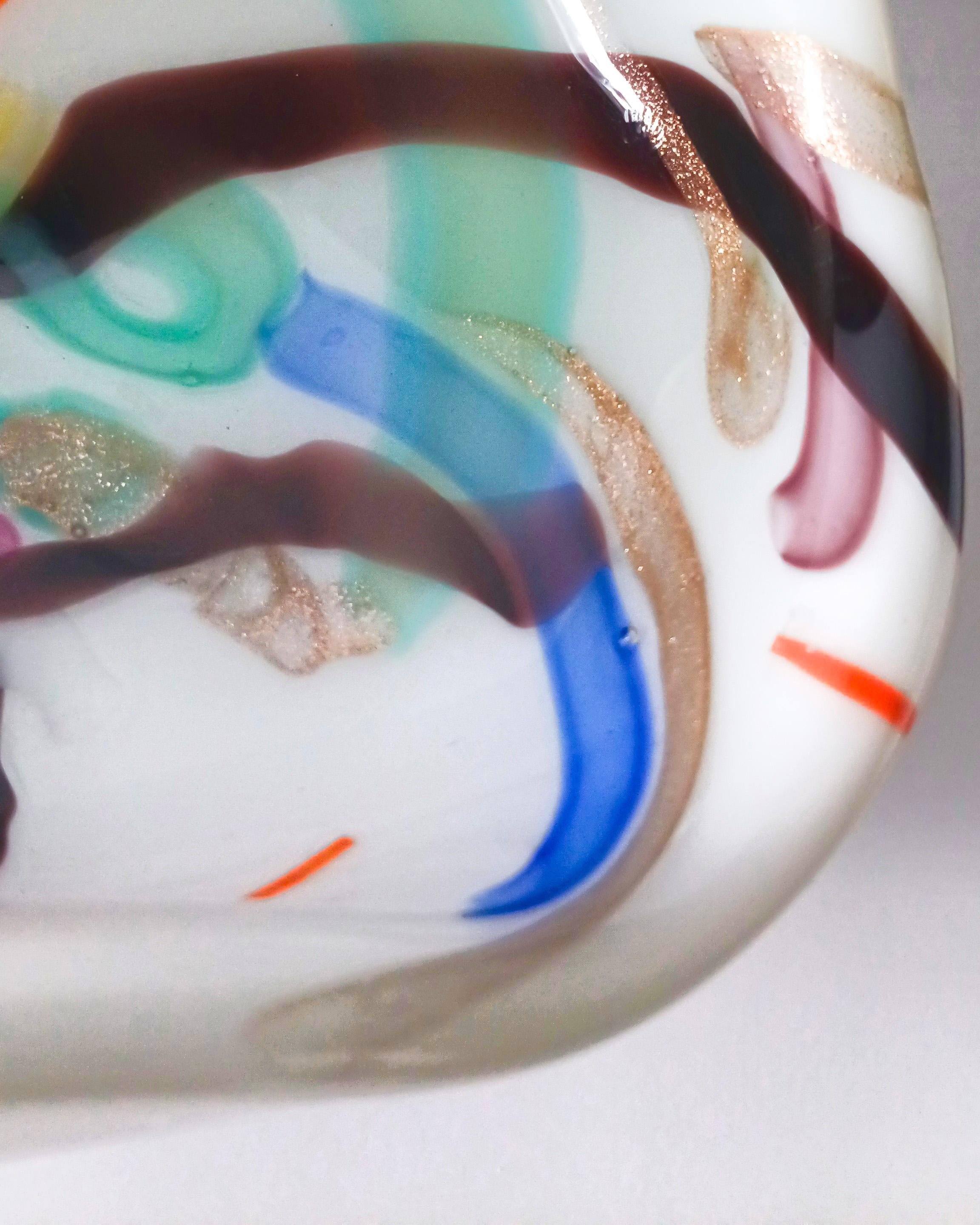 A colourful and abstract Murano glass bowl, handcrafted in Italy circa 1960s. Formed from lattimo glass—the Italian version of milk glass—cased within a clear crystal layer, the piece is softly circular with a gentle indentation along one side,